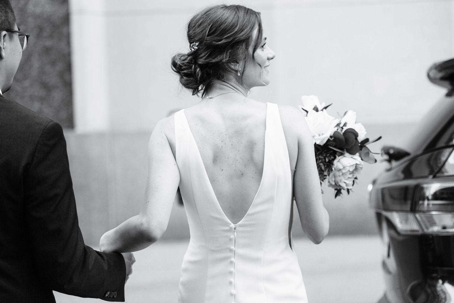 a black and white photo of a bride facing away from the camera as she interacts with guests