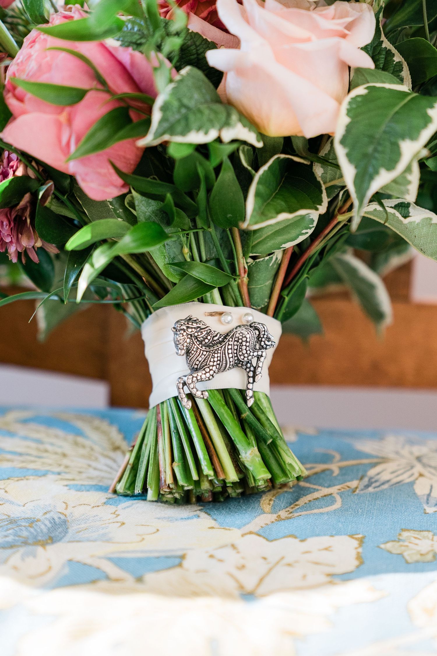 a detail shot of a bridal bouquet showcases a pin of a horse