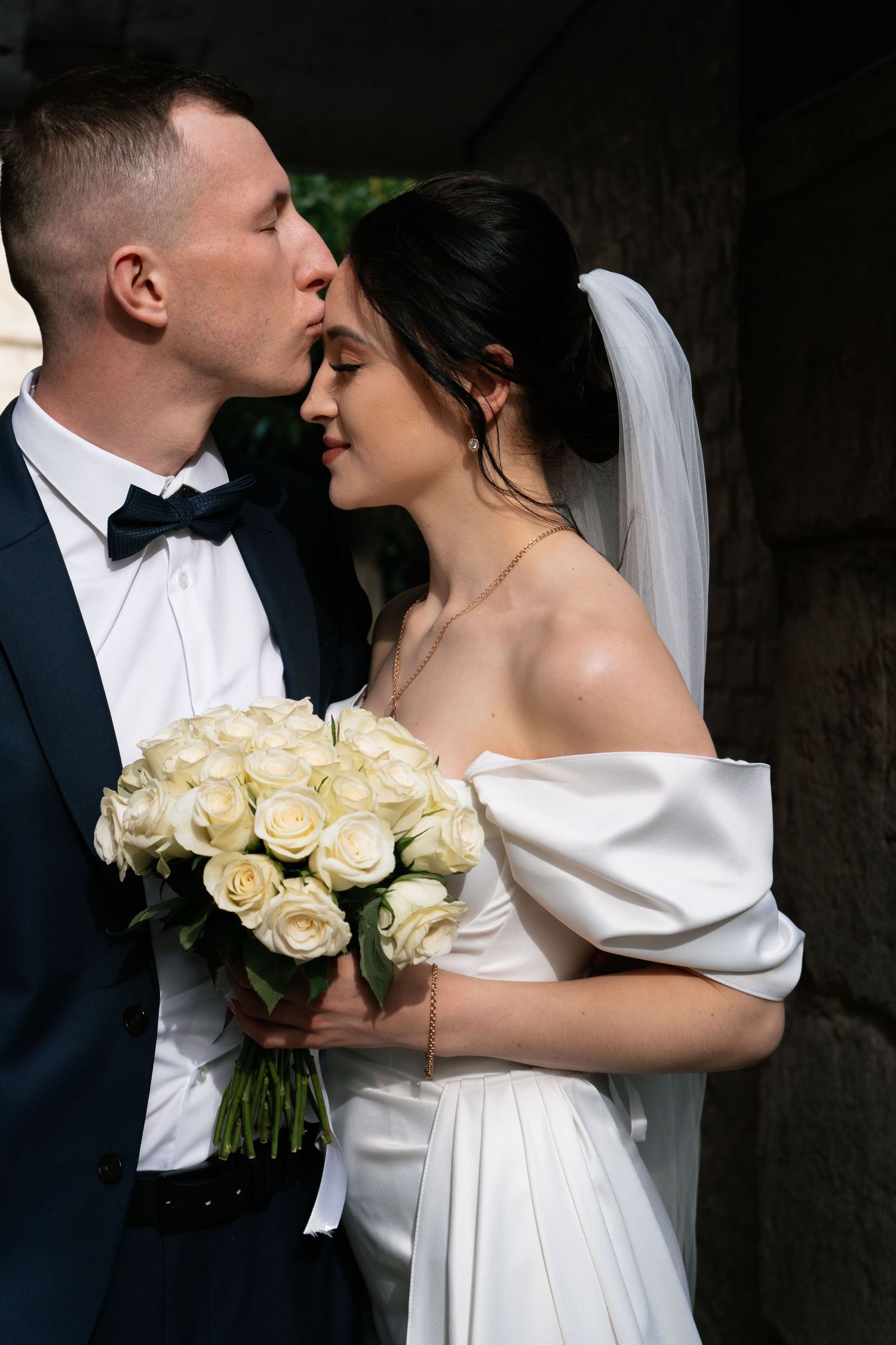 Romantic wedding portrait with white roses and elegant attire.
