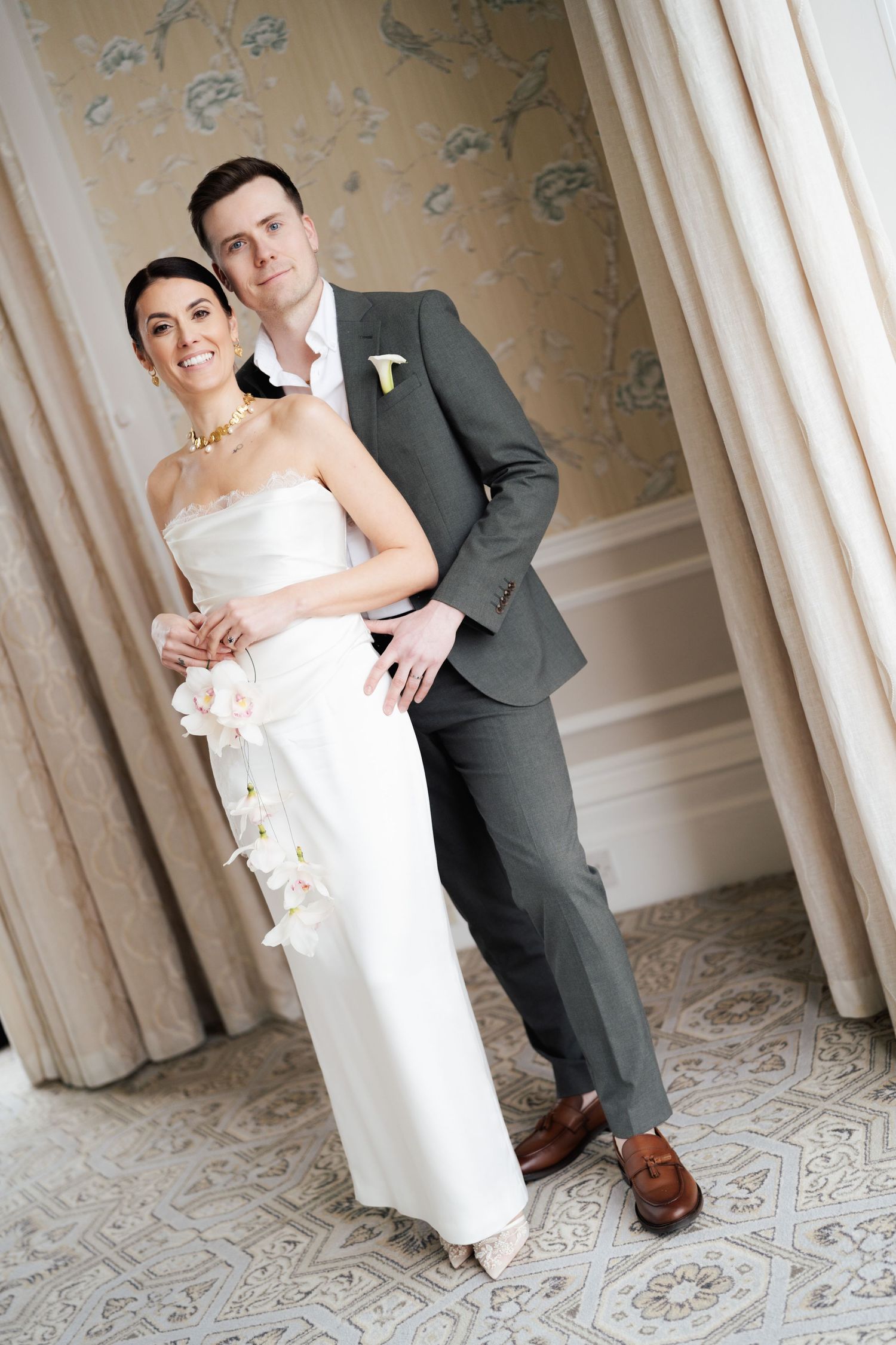 Elegant wedding couple poses together against ornate wallpaper in a series of romantic formal portraits.