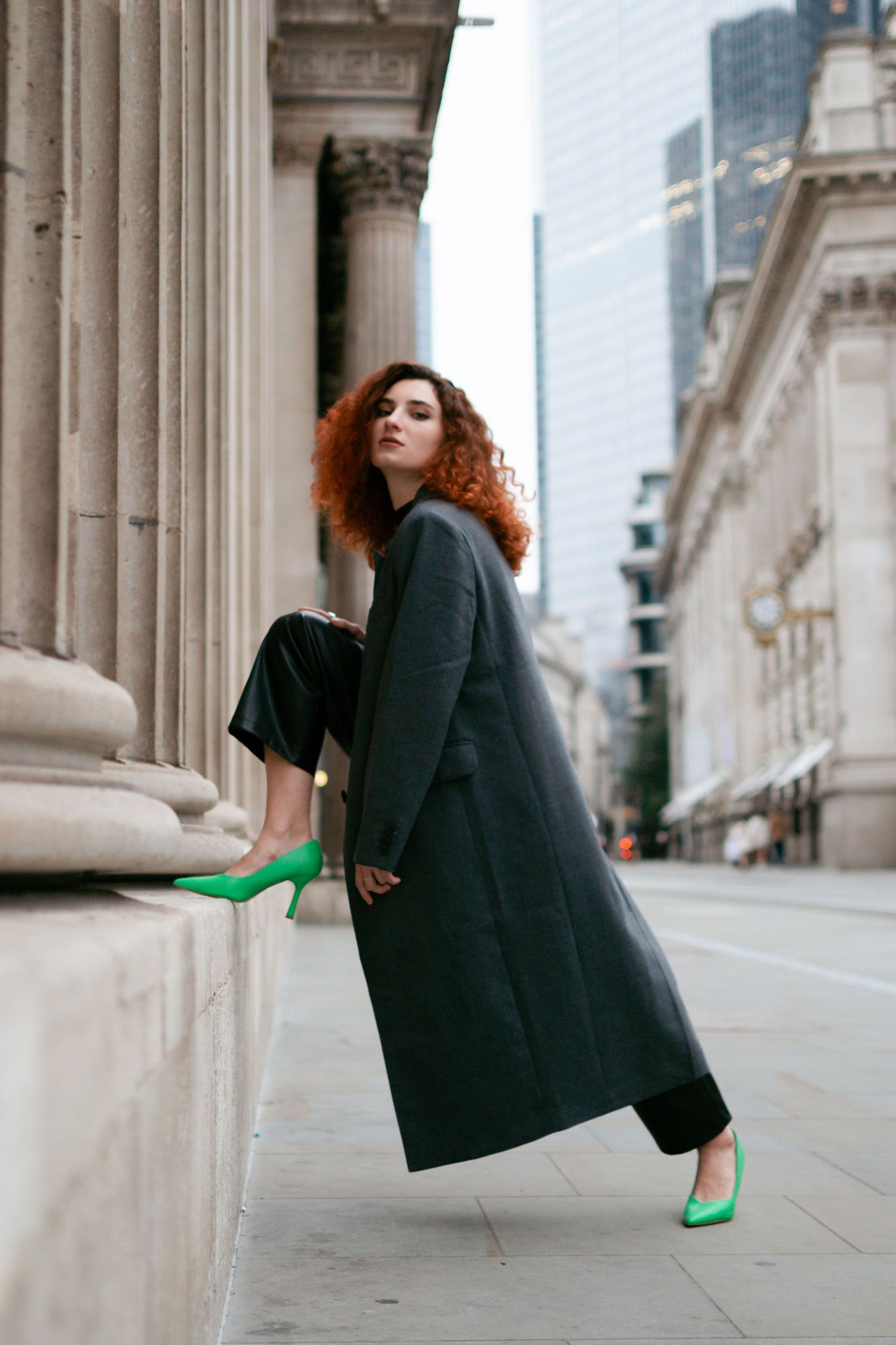 Urban fashion shoot with bright green shoes contrasting against classical architecture.