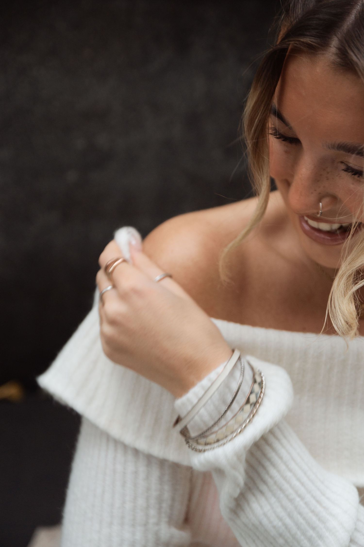 Person wearing a cozy white ribbed sweater shown in close-up detail against a dark background.
