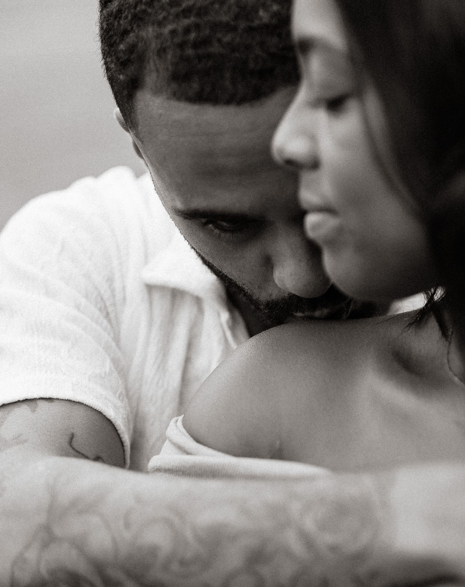 An intimate black and white portrait captures a tender moment between a couple.
