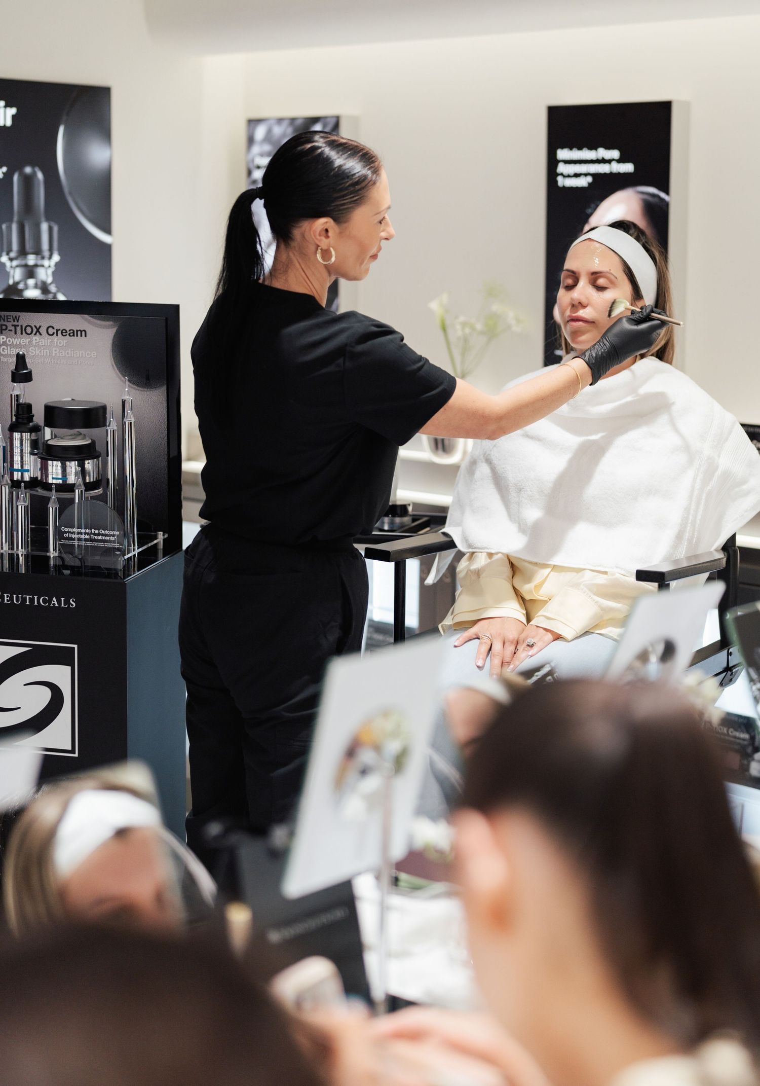 Esthetician applying facial treatment to client in beauty salon during skincare demonstration.