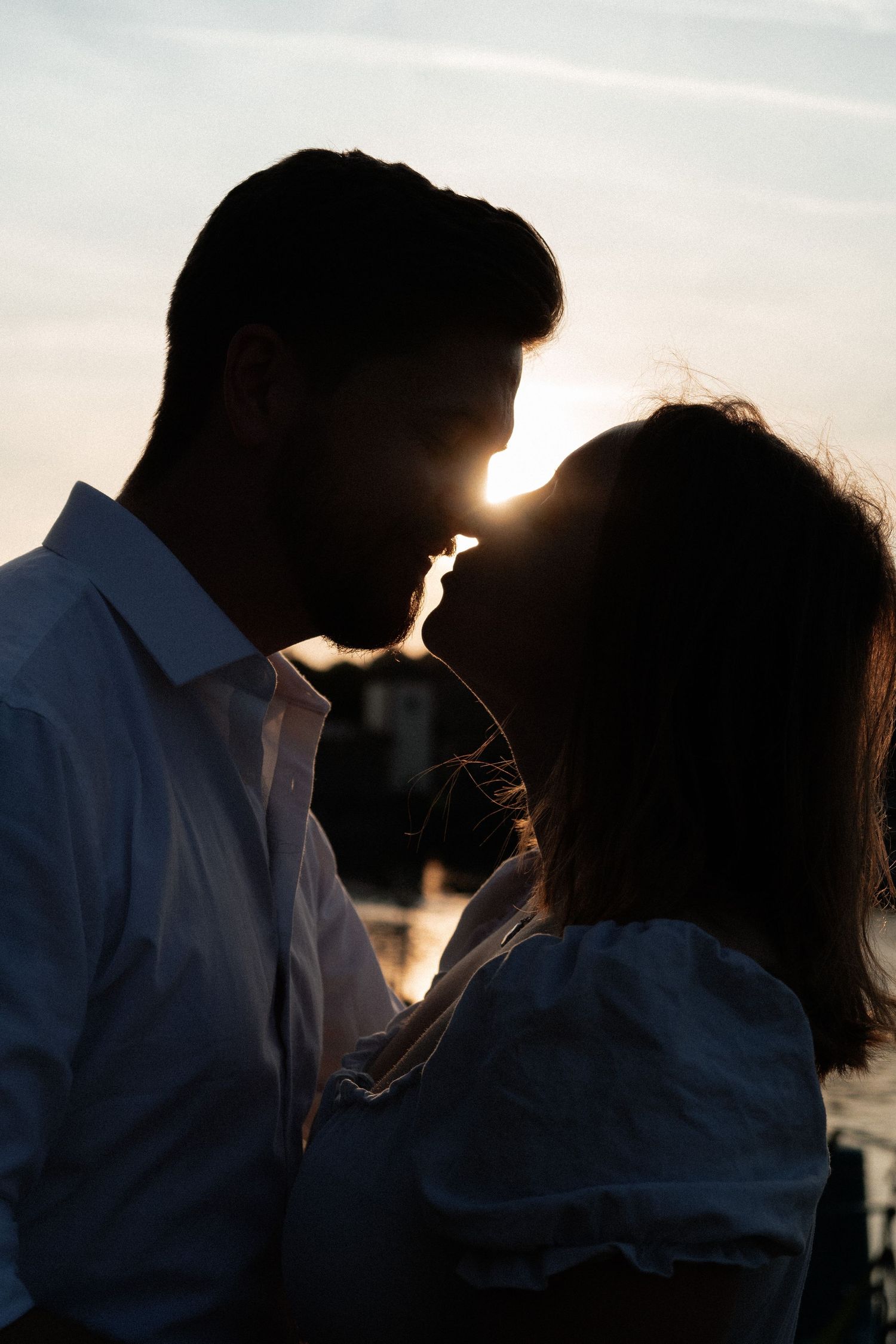 Romantic silhouettes of a couple sharing an intimate moment against a glowing sunset backdrop.