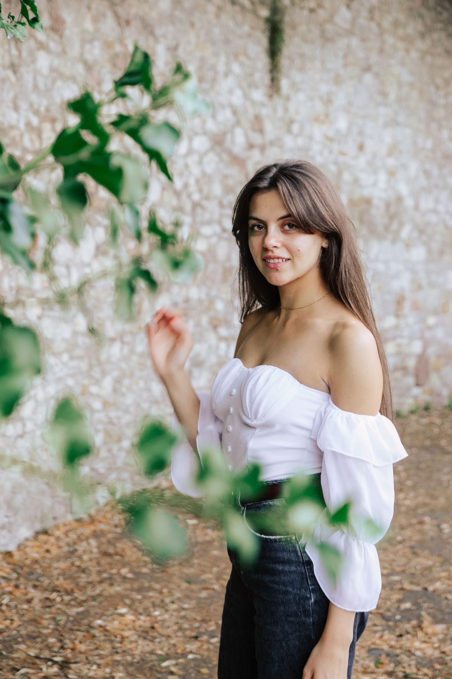 Artistic fashion photos captured against a textured stone wall with green leaves.