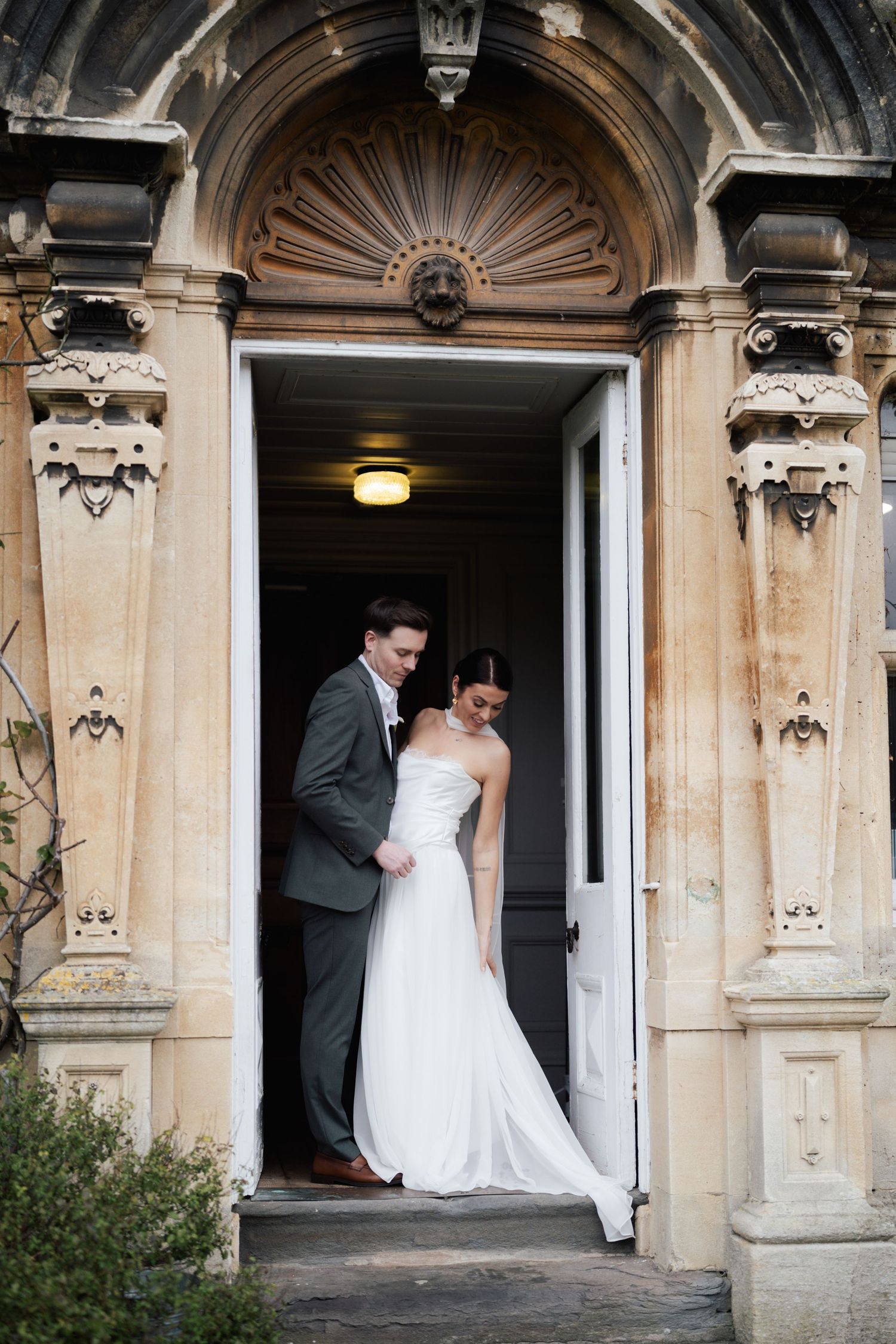 A wedding couple stands in a series of elegant stone doorways at a historic venue, captured in multiple romantic poses.