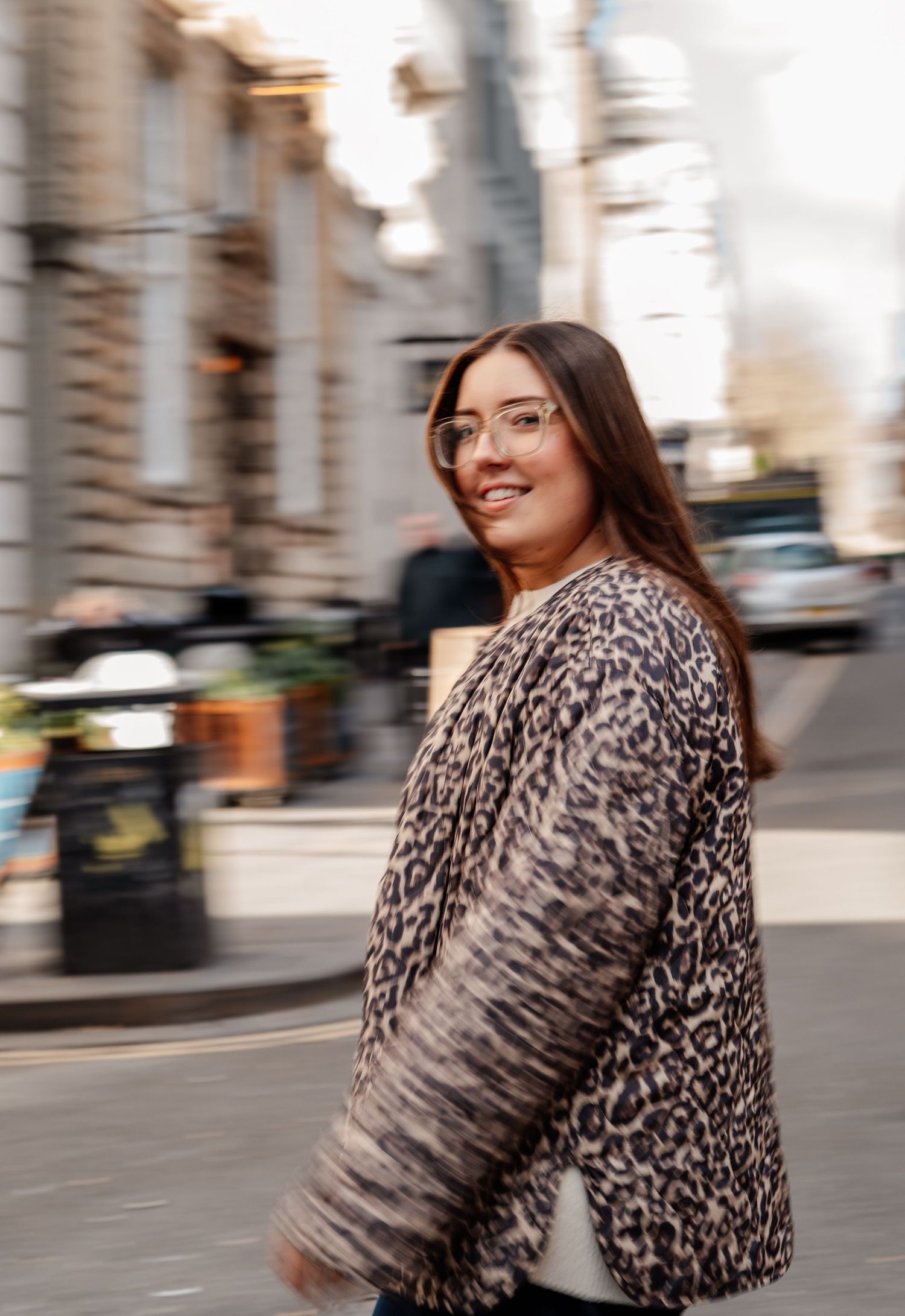 Street style photo in animal print coat with urban background.