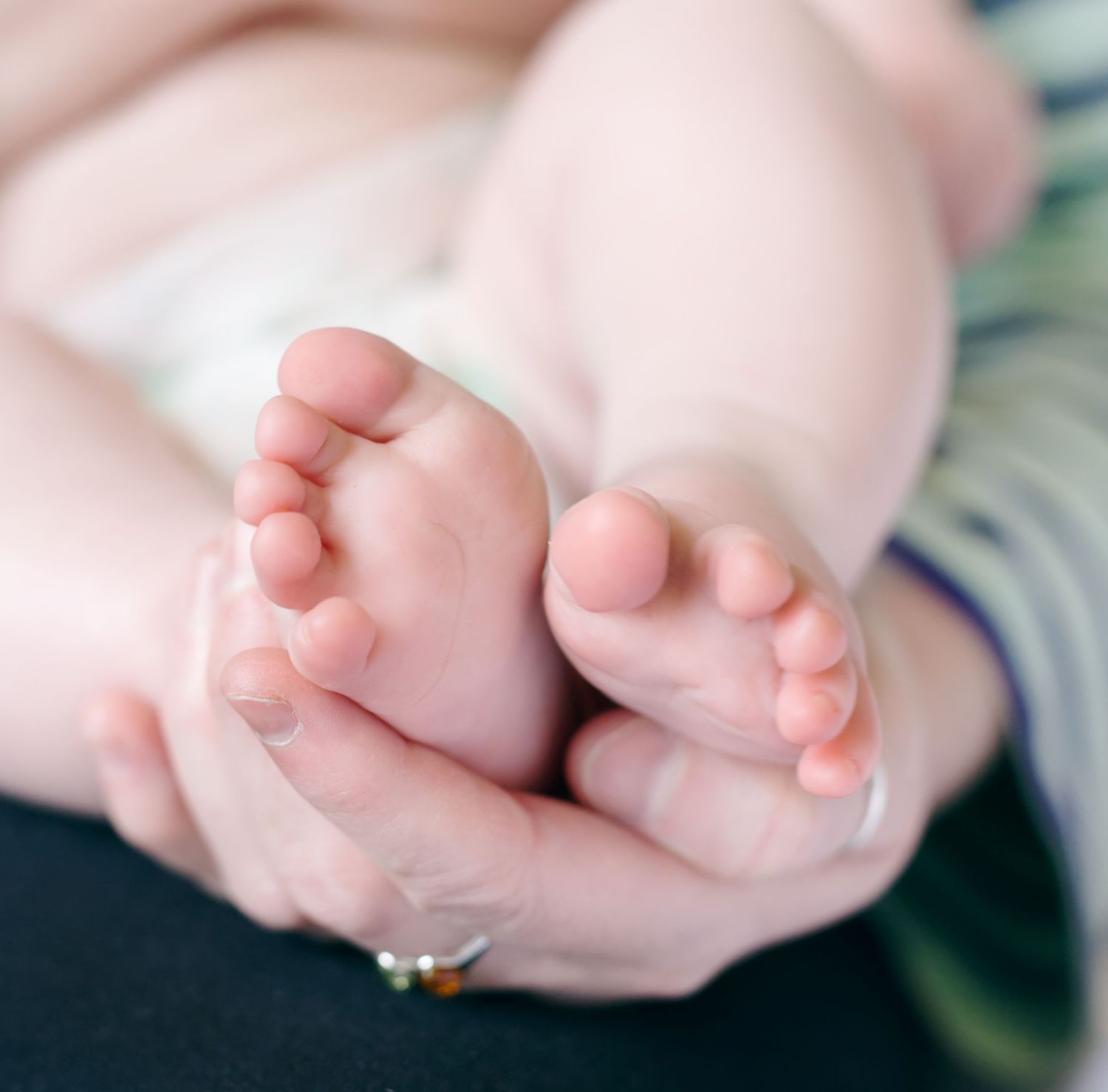 Close-up of baby's tiny feet being held gently by adult hands, showing gentle parent care