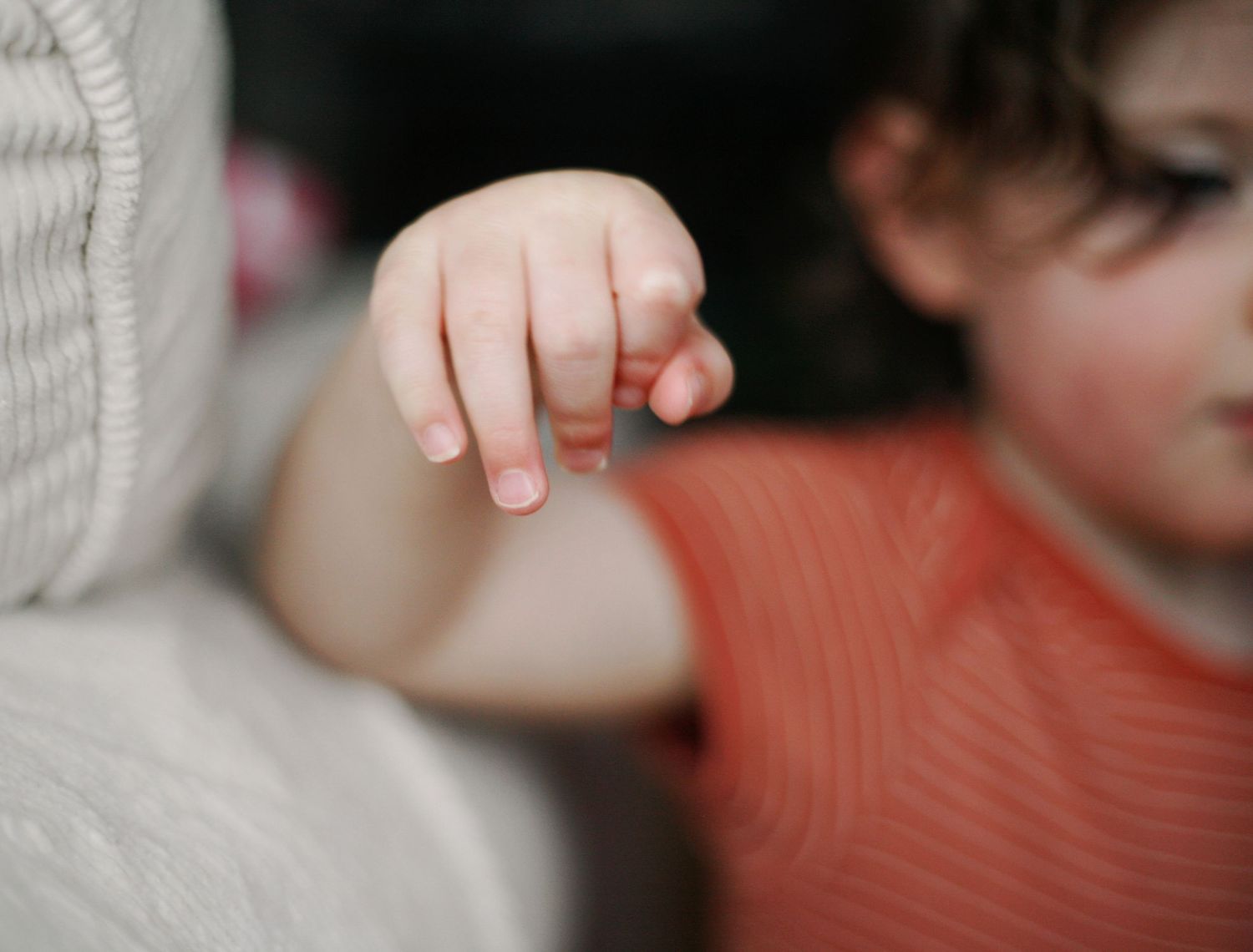 A small child's hand reaches out against a soft blurred background
