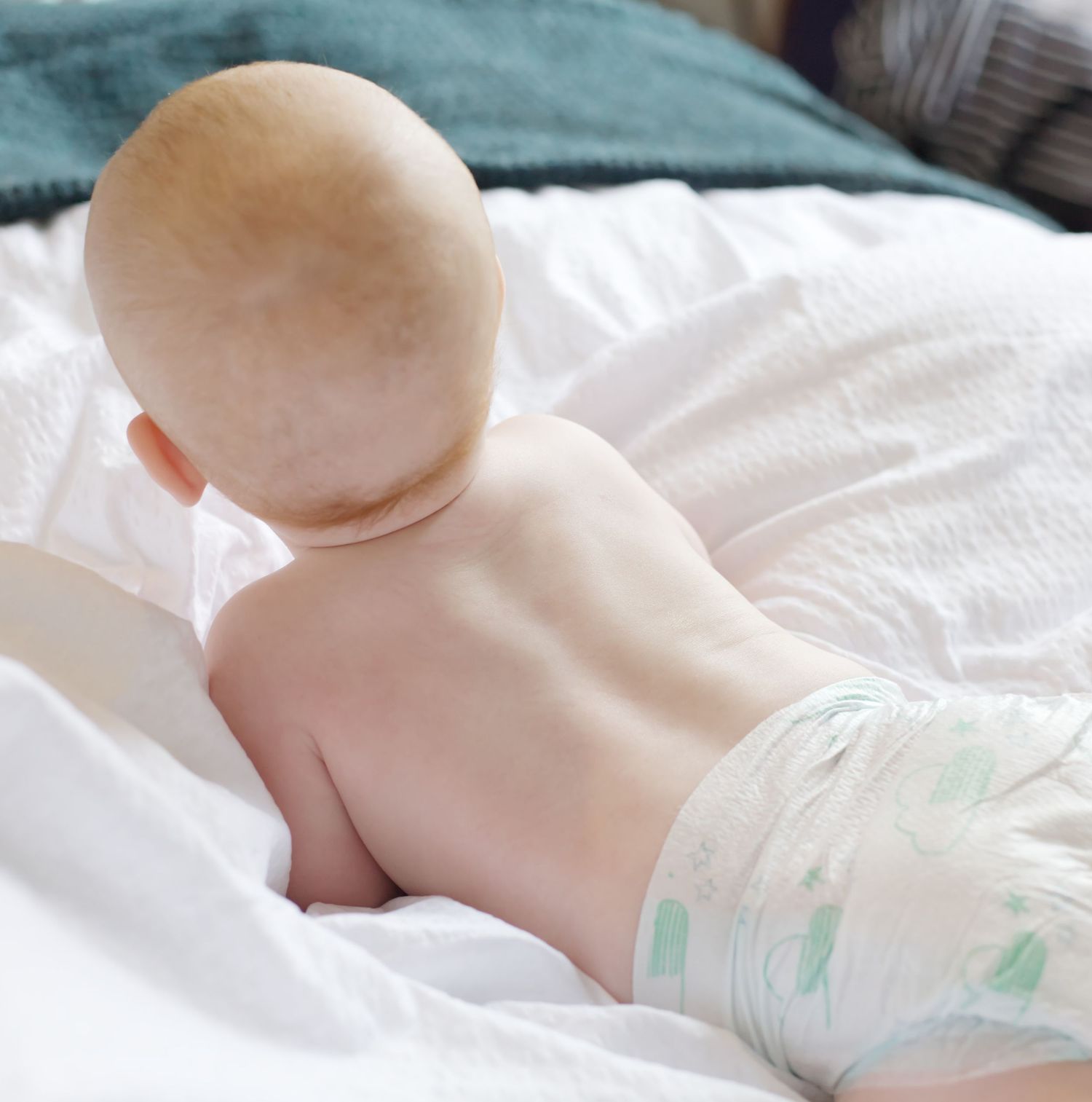 Close-up view of a newborn resting on soft bedding with natural lighting