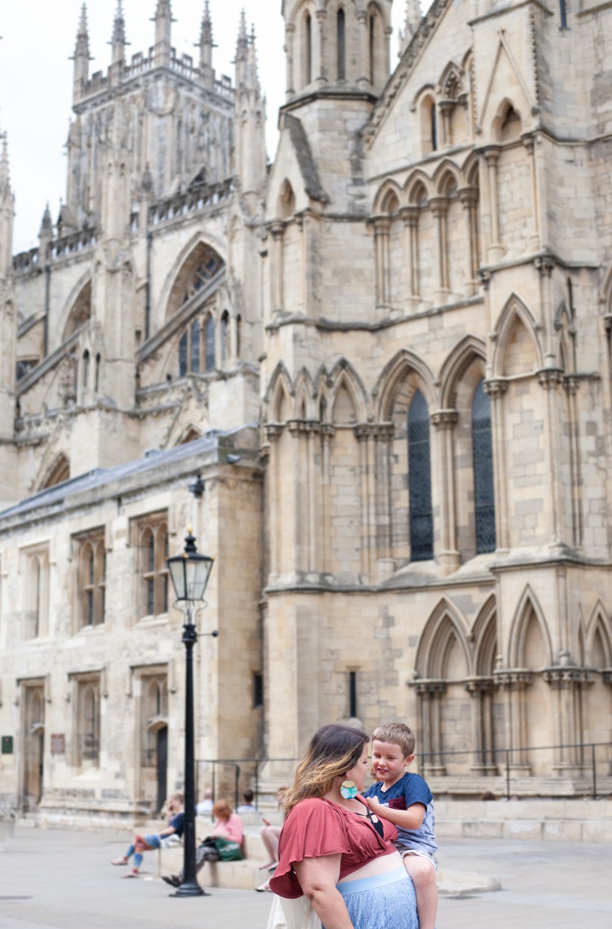 Mother and child having a sweet moment in front of  the Gothic architecture of York Minster cathedral with ornate stone details and arches.