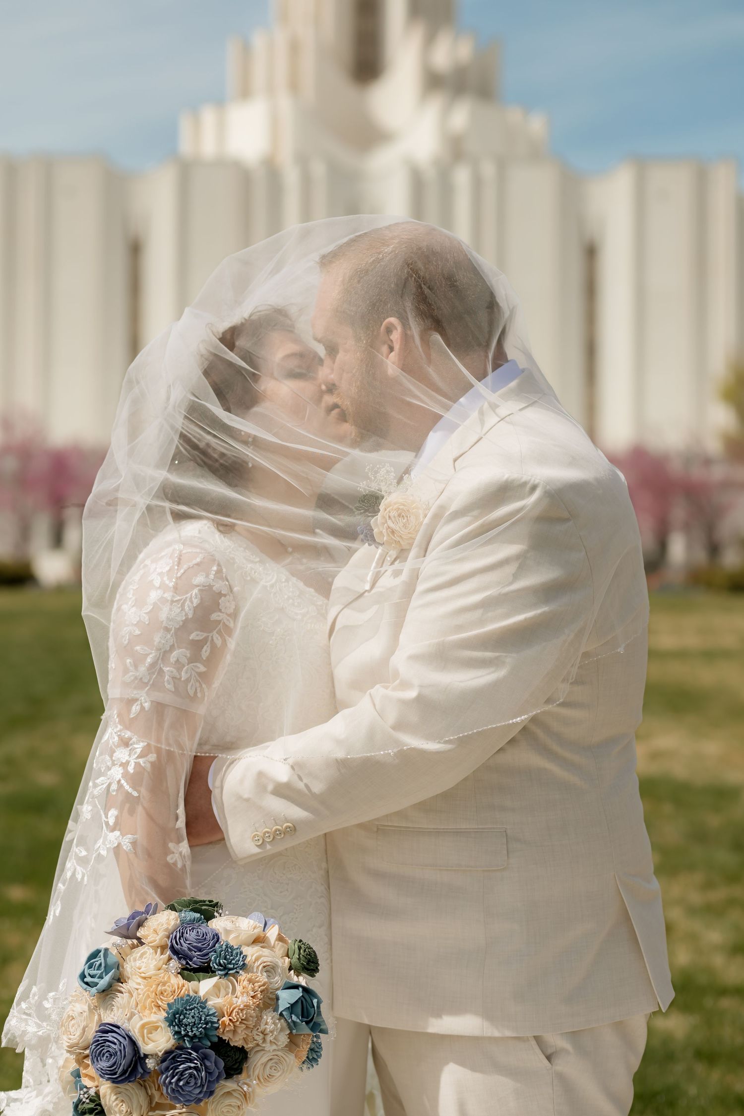 Wedding picture of couple kissing infant of temple on wedding day in Utah
