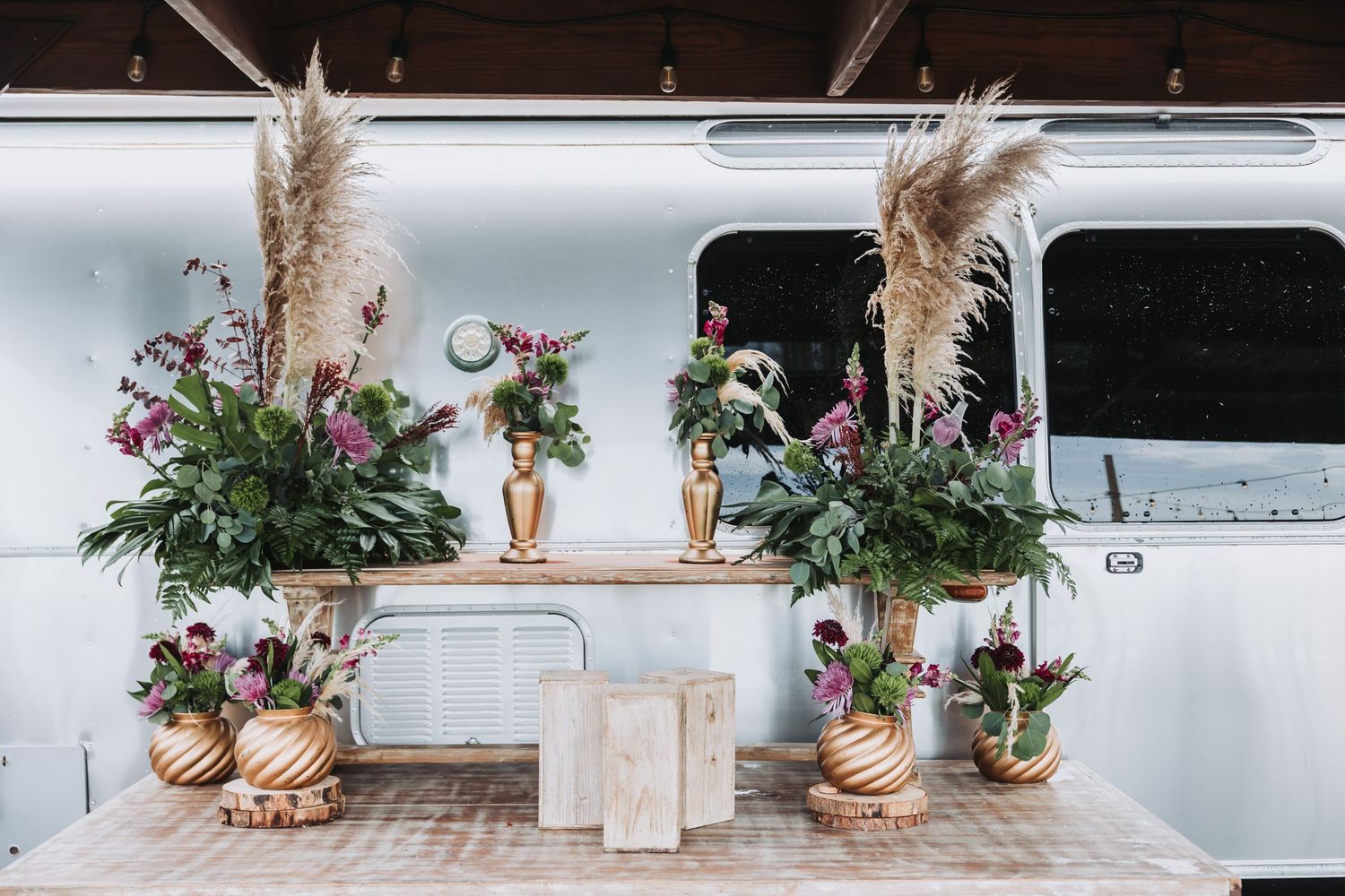 Rustic wedding reception table settings with dried pampas grass and floral arrangements in neutral tones.