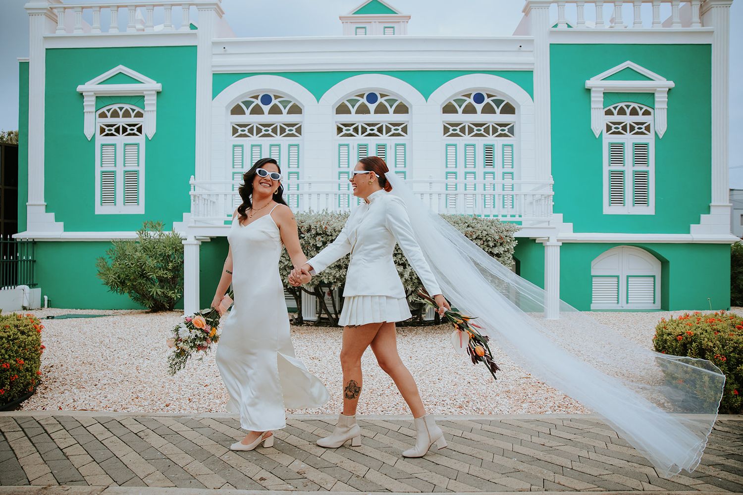 A series of wedding photos showing playful moments against a vibrant mint green colonial building backdrop.