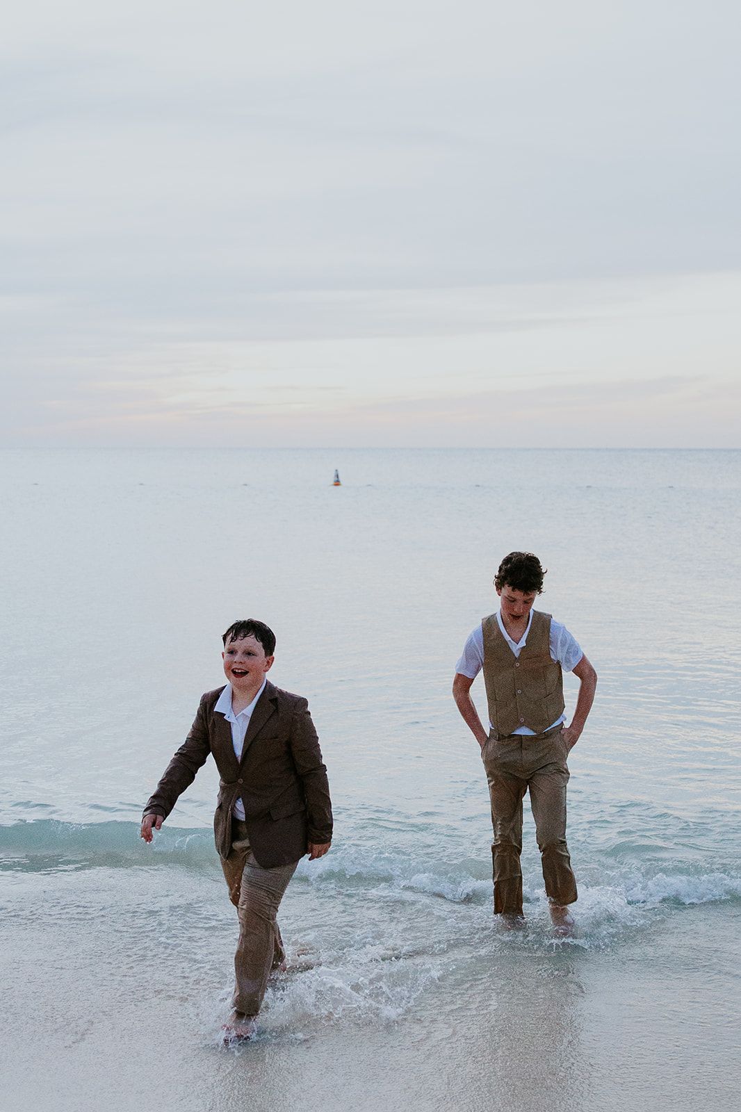 A person wearing brown clothing walks progressively deeper into calm ocean waters in a sequence of six photos.