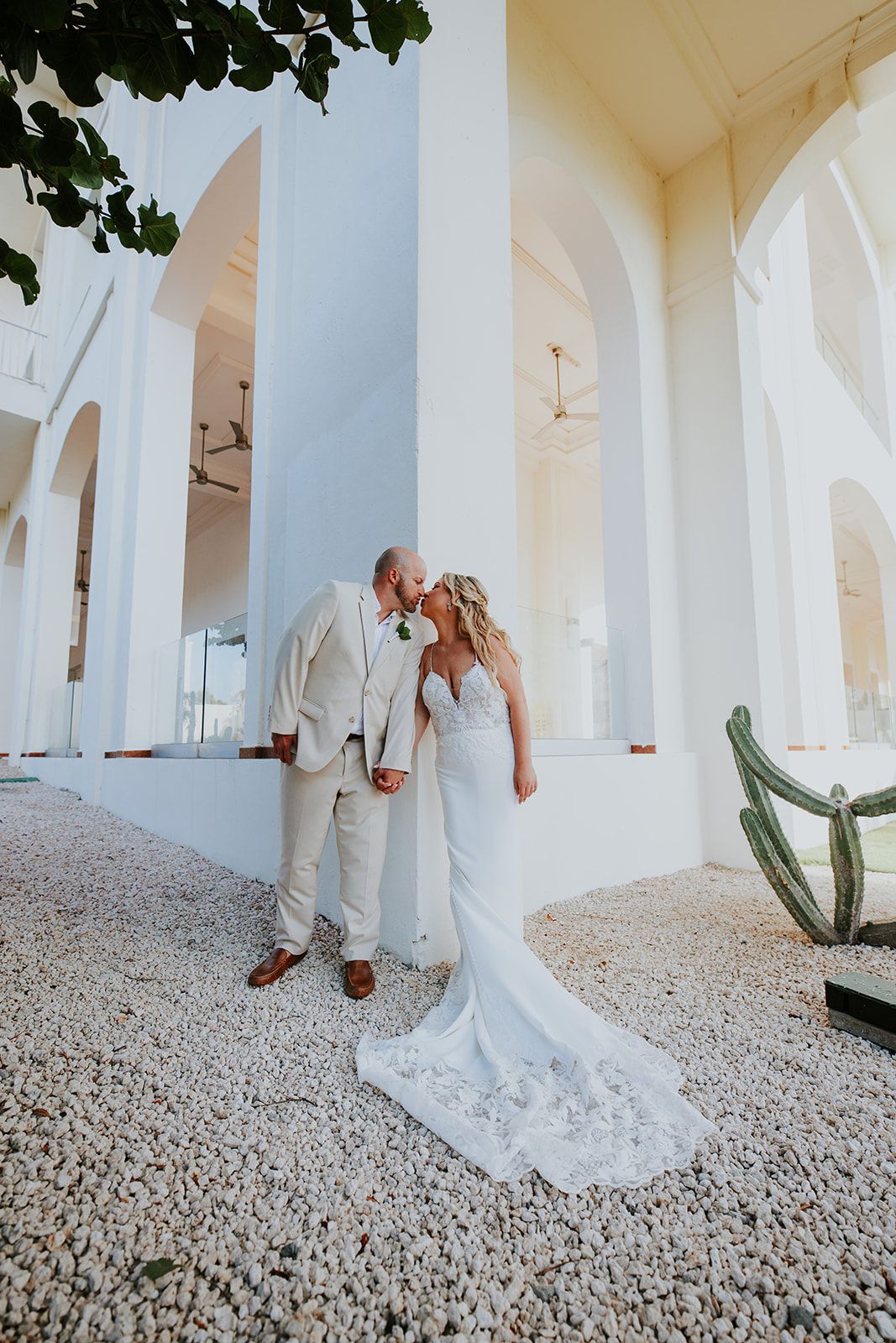 Elegant wedding couple poses against white architectural columns and arches.