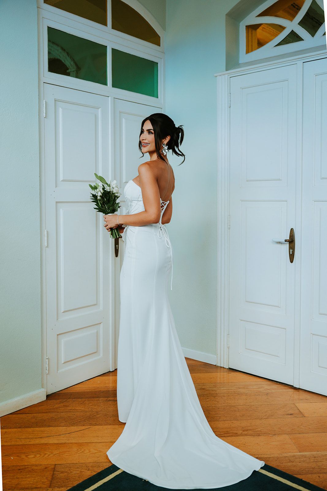 A sequence showing the elegant flow of a white wedding dress train against white doors and wooden flooring.