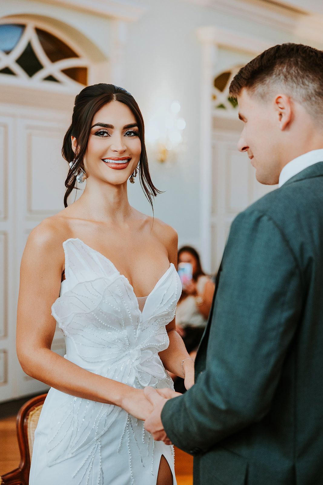 A couple shares joyful moments during their wedding ceremony in an elegant white-walled venue.