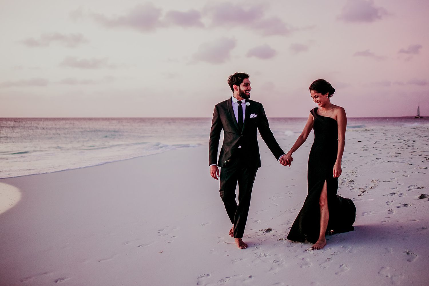Romantic beach wedding photoshoot during sunset with pink and purple sky.