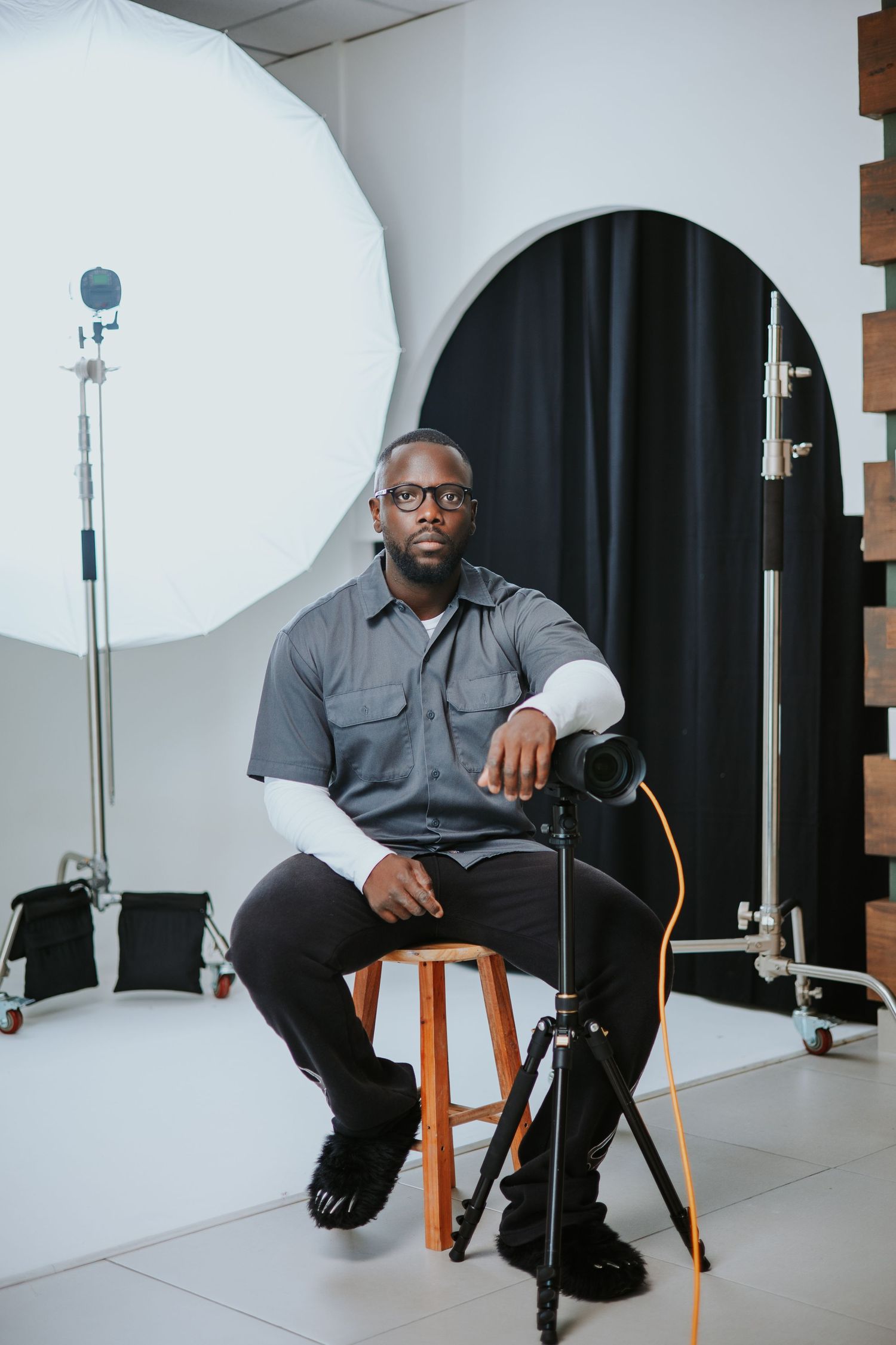 Professional photographer in studio setting with lighting equipment and backdrop.