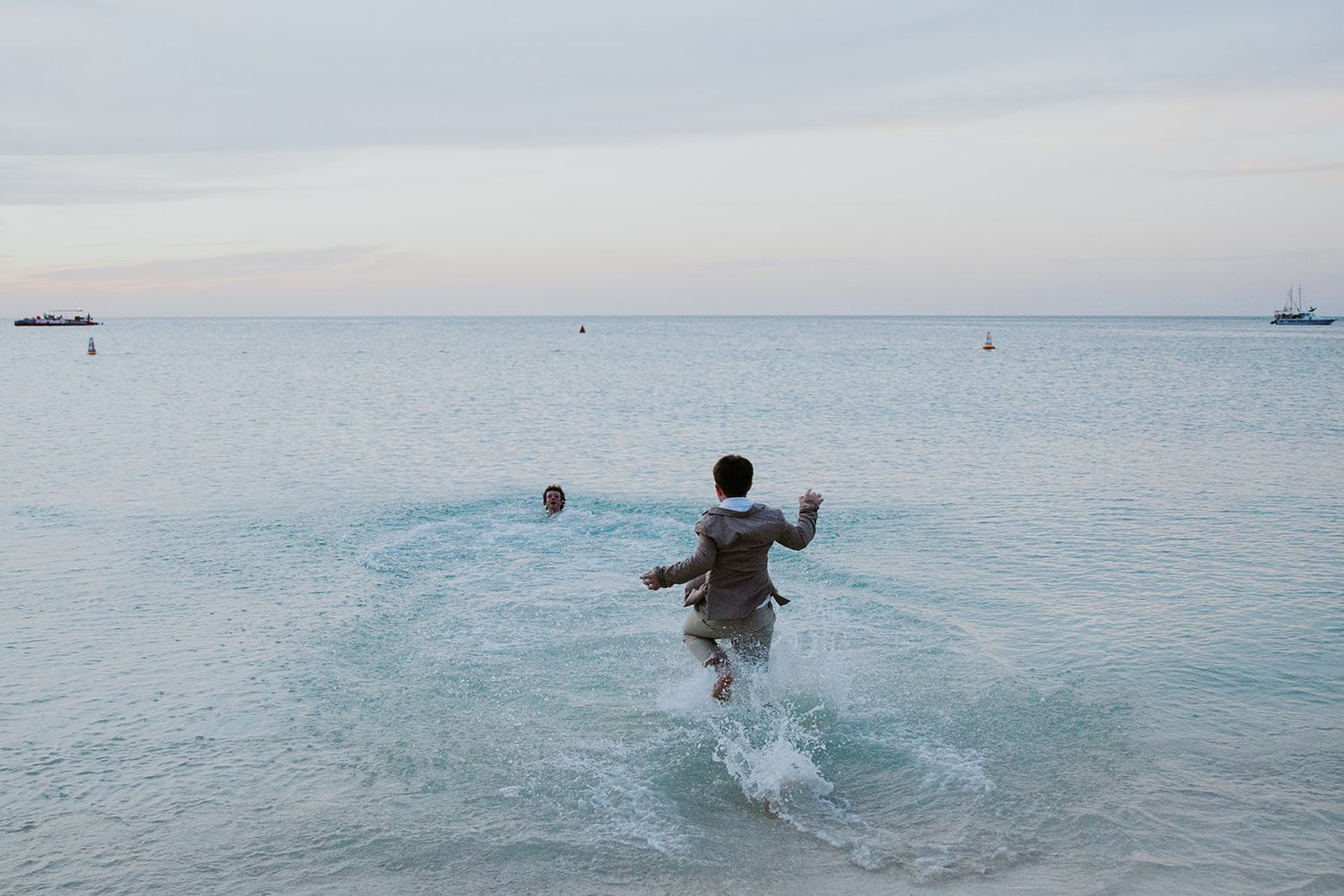 A sequence of photos showing someone joyfully running and splashing into the ocean at sunset.