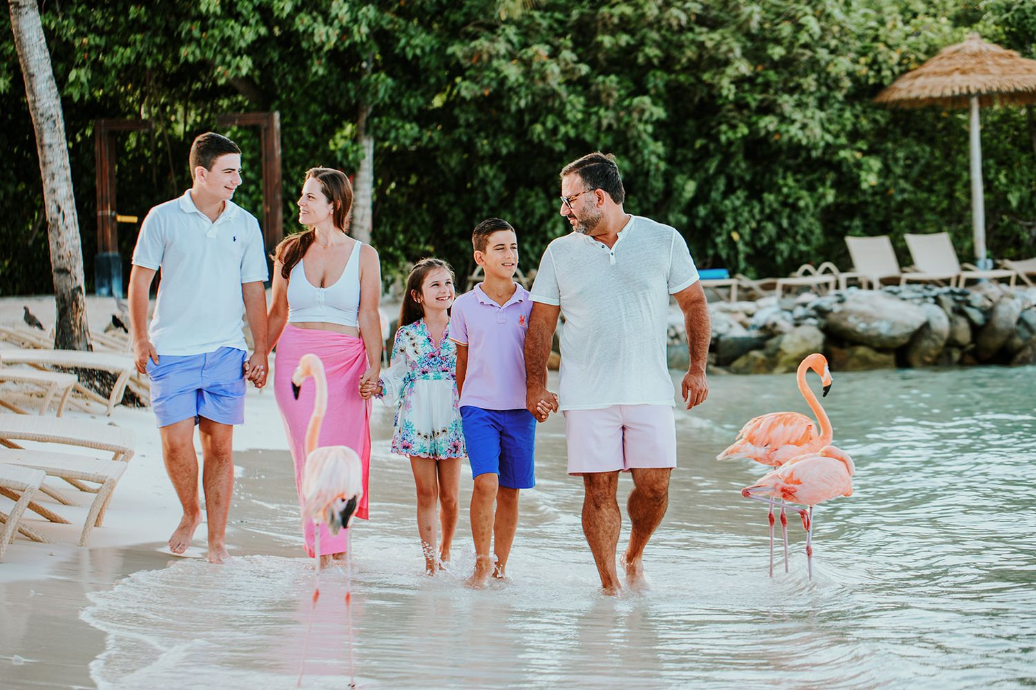 Family members walk together along a pristine tropical beach with turquoise waters.