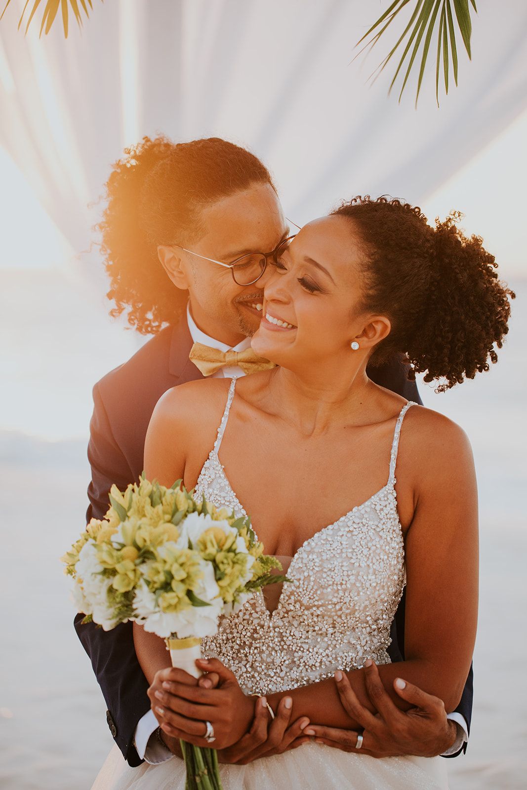 Close up of elegant white bridal bouquet with yellow flowers against light background.