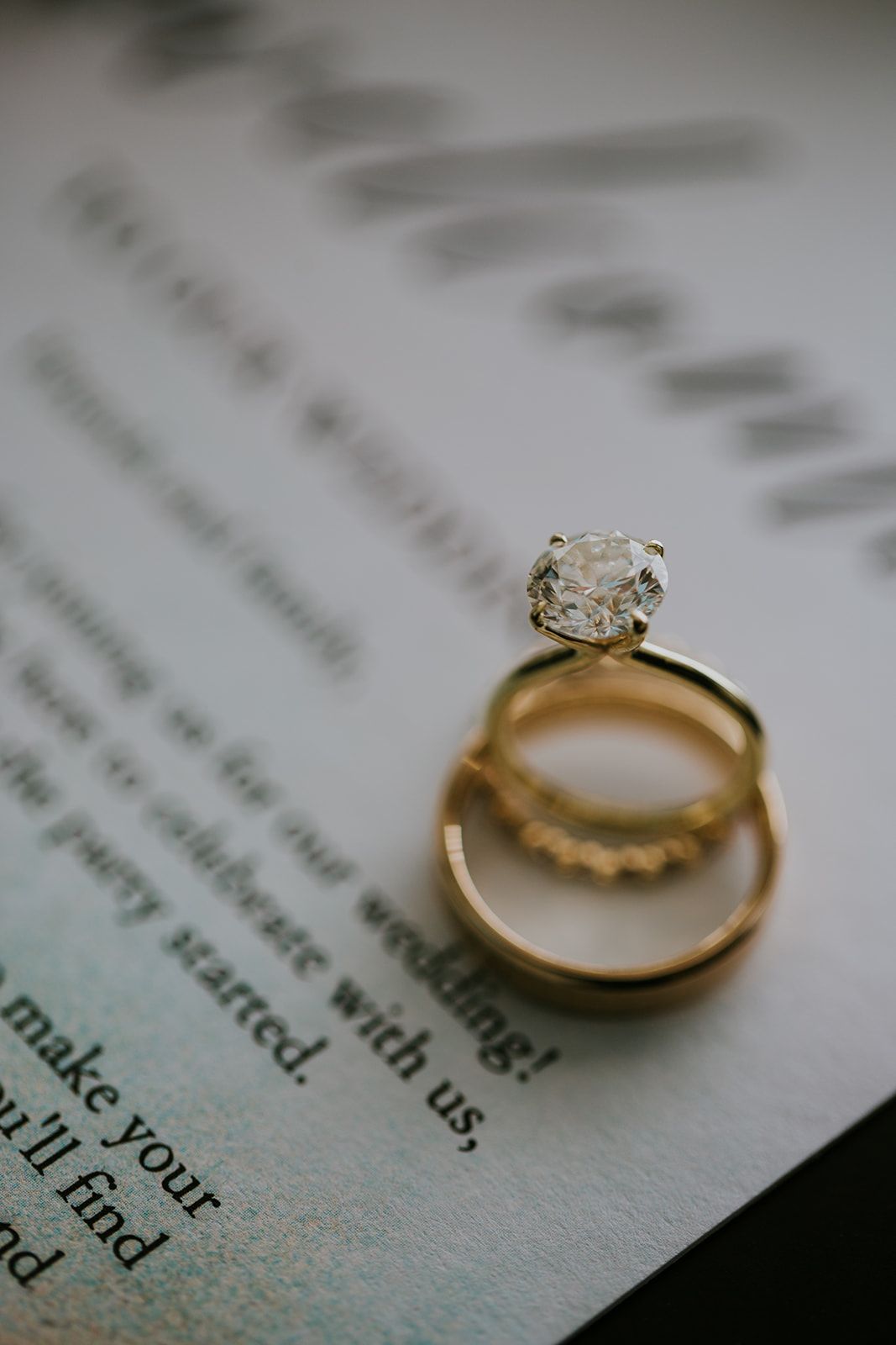 Close-up of wedding rings casting shadows on book pages with text visible beneath.