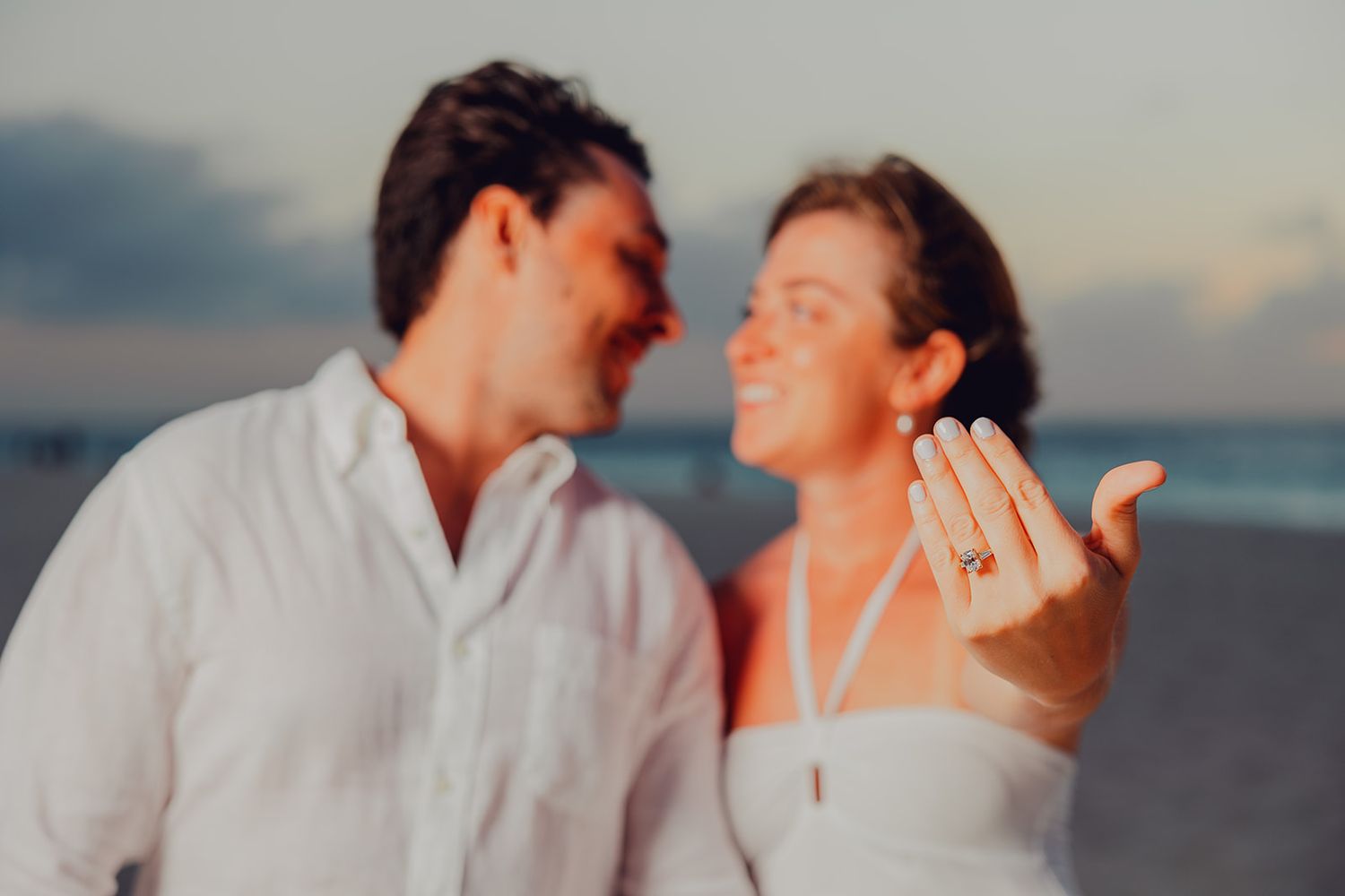 Romantic couple embracing at sunset on the beach during a photoshoot session.
