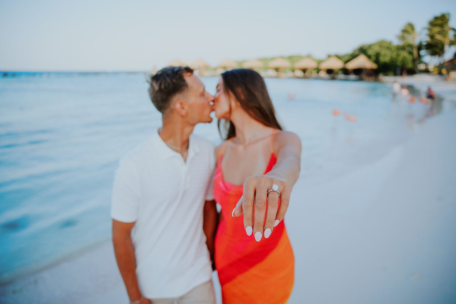 Beachside engagement photography session with turquoise ocean waters in the background.