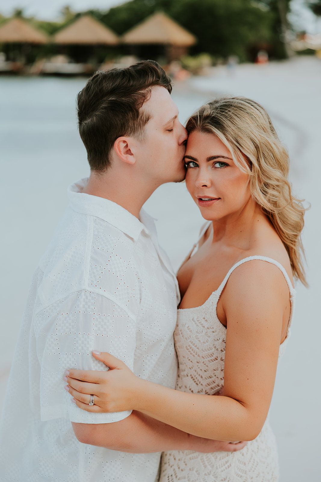 Intimate engagement portrait against light background with tender moment.