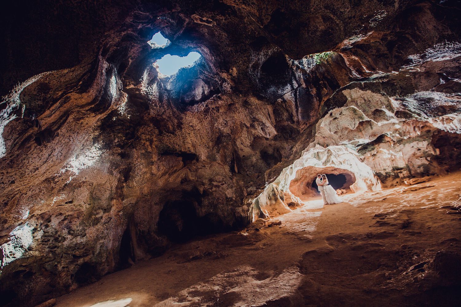 Dramatic cave landscape with natural light streaming through rocky formations.