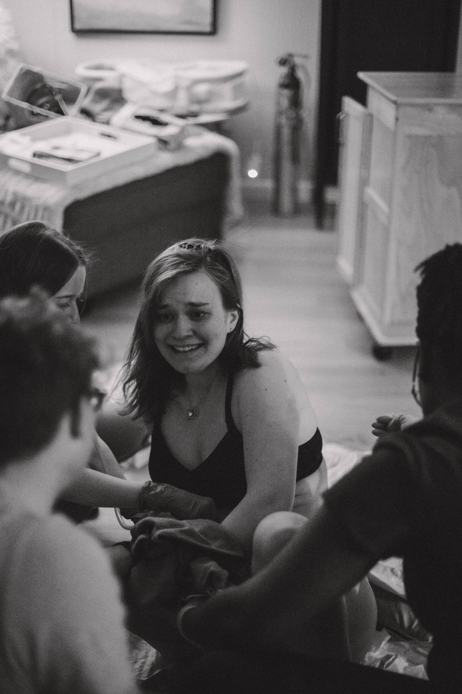 Emotional black and white photo of a woman smiling through tears during home birth labor.