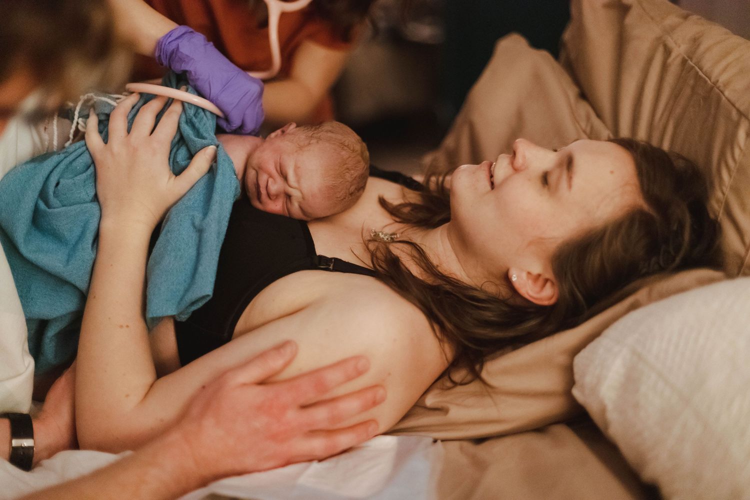 Newborn baby placed on mothers chest immediately after birth by medical team.