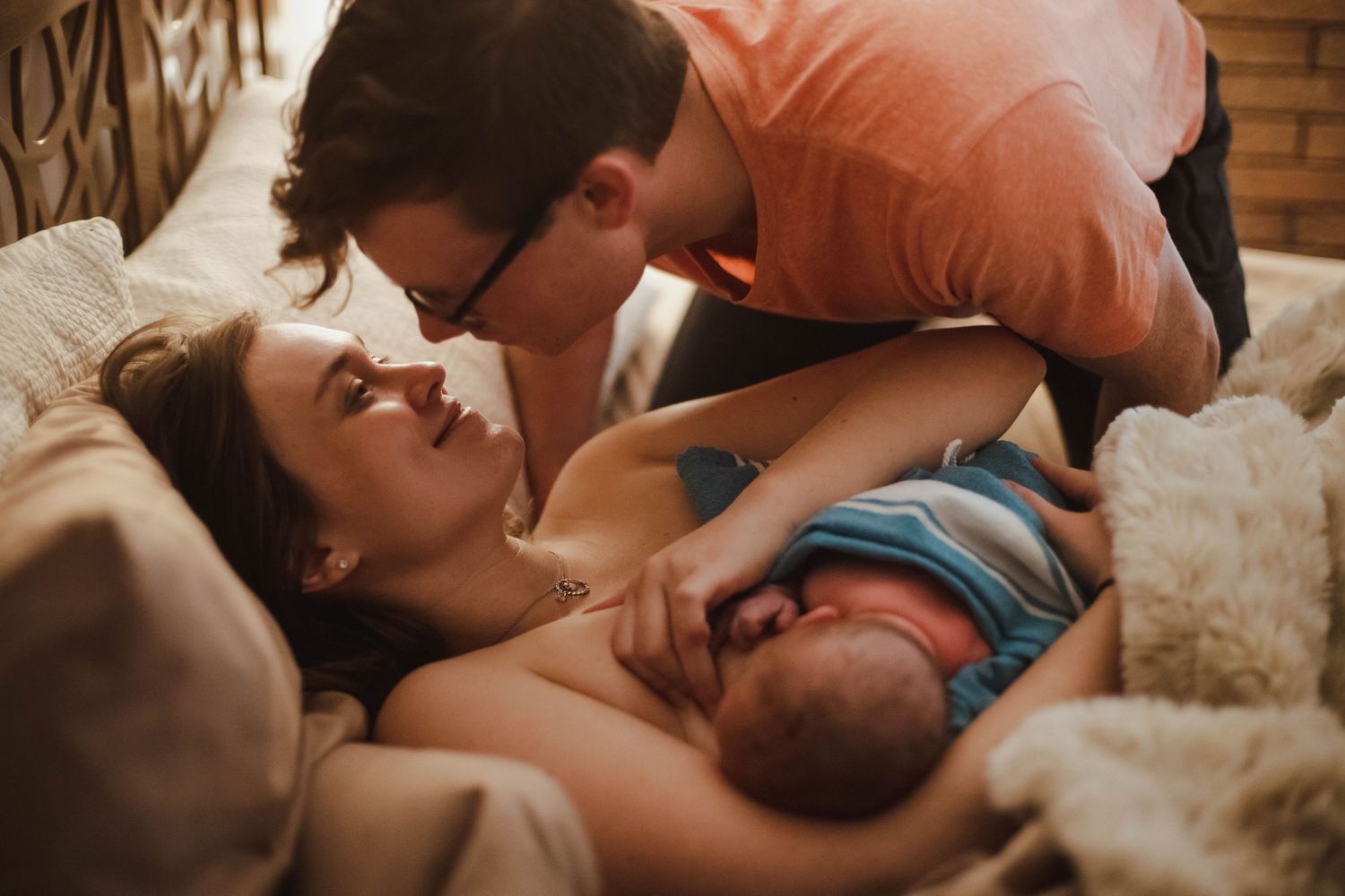 Loving couple sharing a tender moment with their newborn baby after home birth.