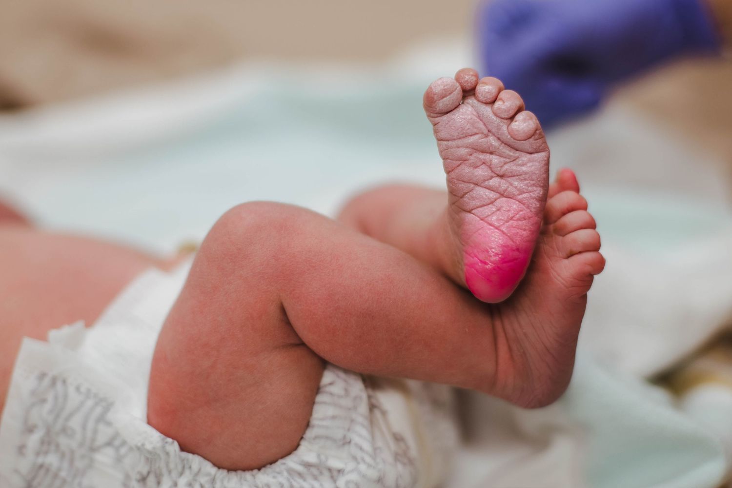 Close-up of a newborn baby's foot being inked for a footprint during a home birth checkup.