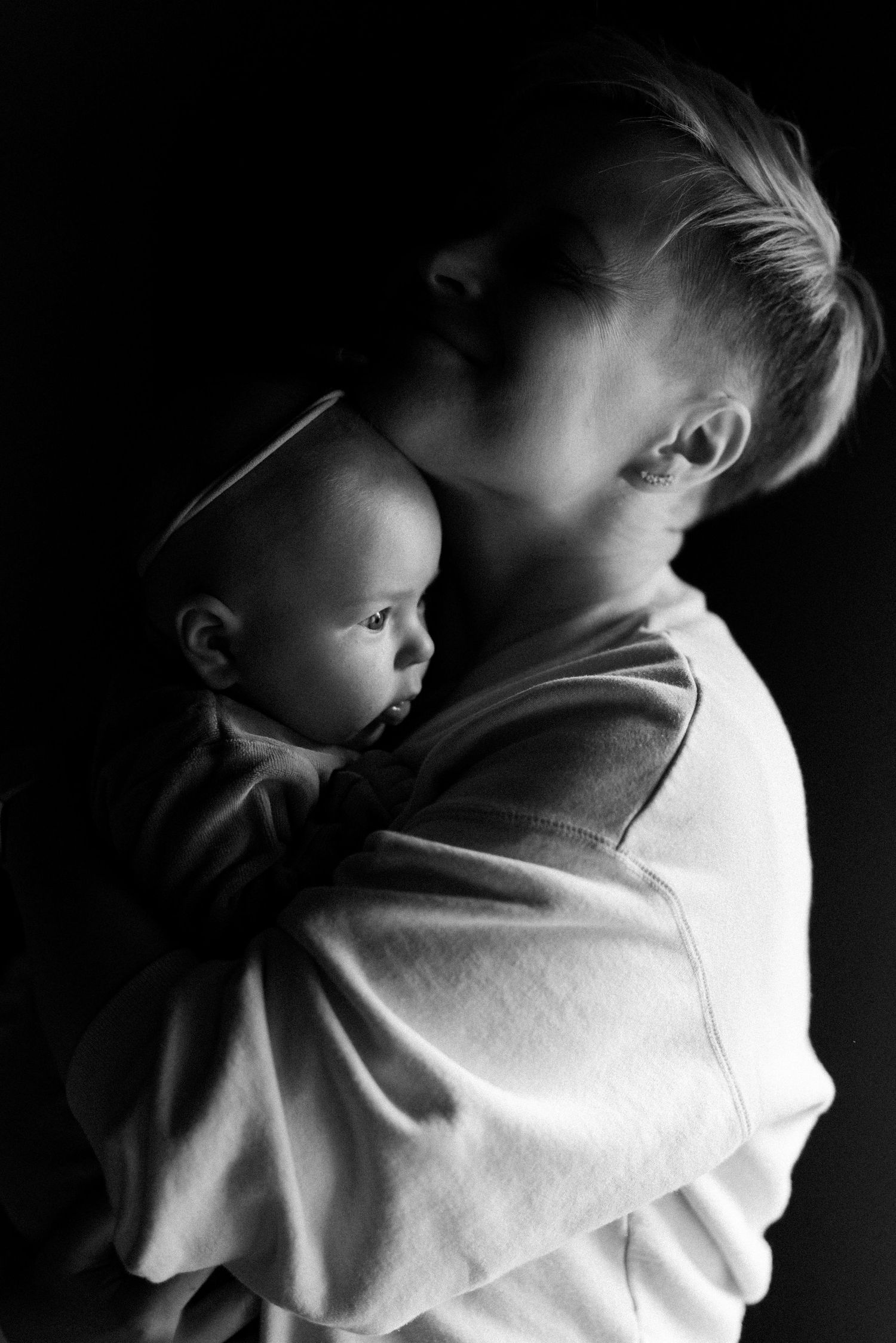 Dramatic black and white portrait showing intimate embrace in low key lighting.