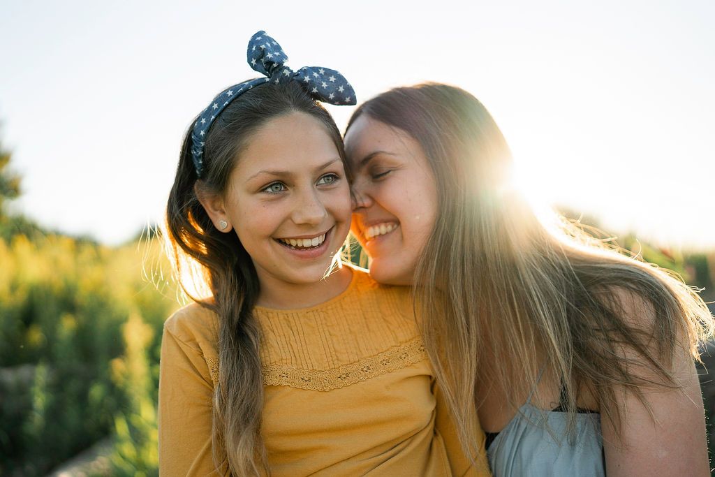 Two friends sharing a joyful moment in golden sunlight wearing yellow and blue.