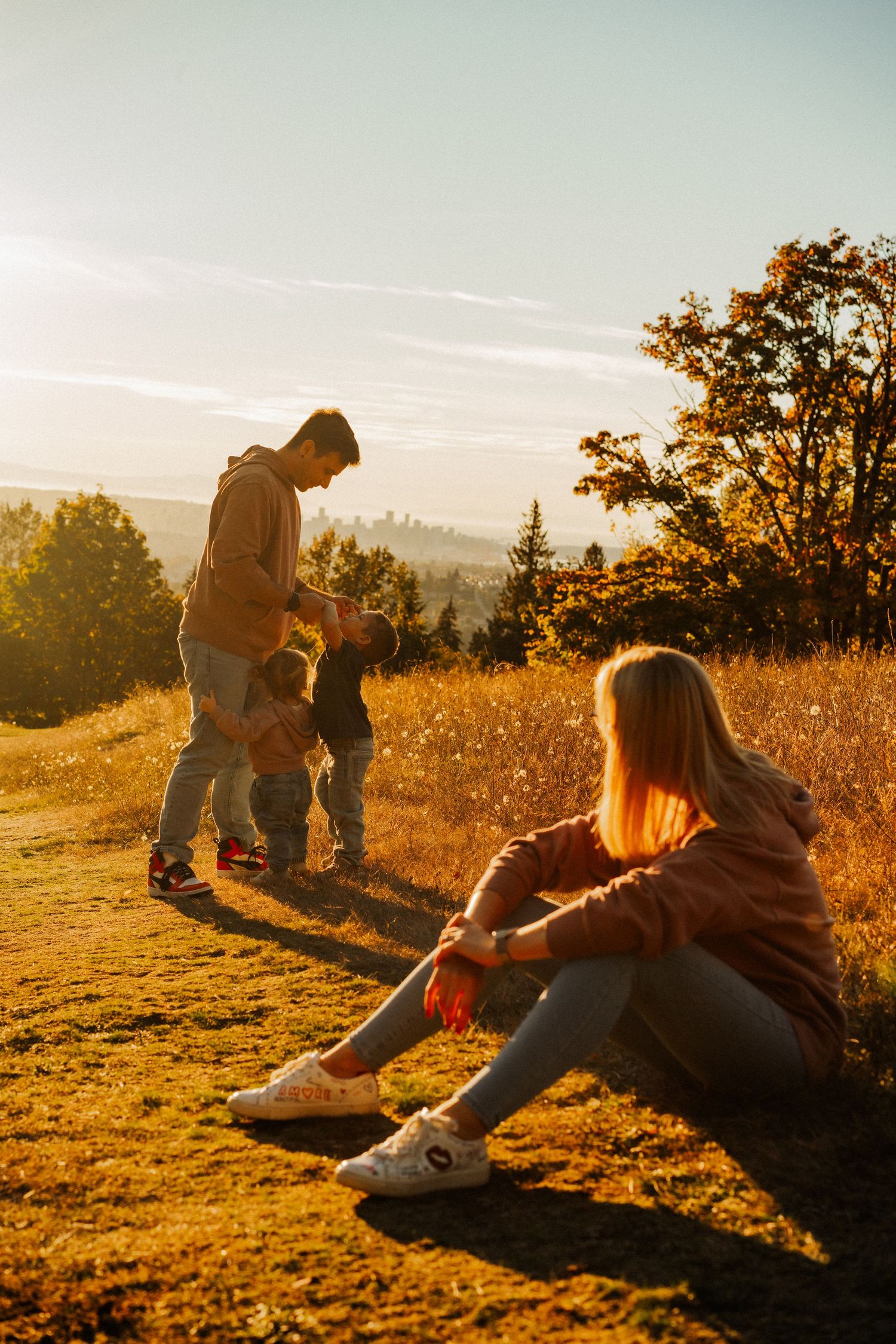 Friends enjoying a golden sunset together on a grassy hillside during autumn.