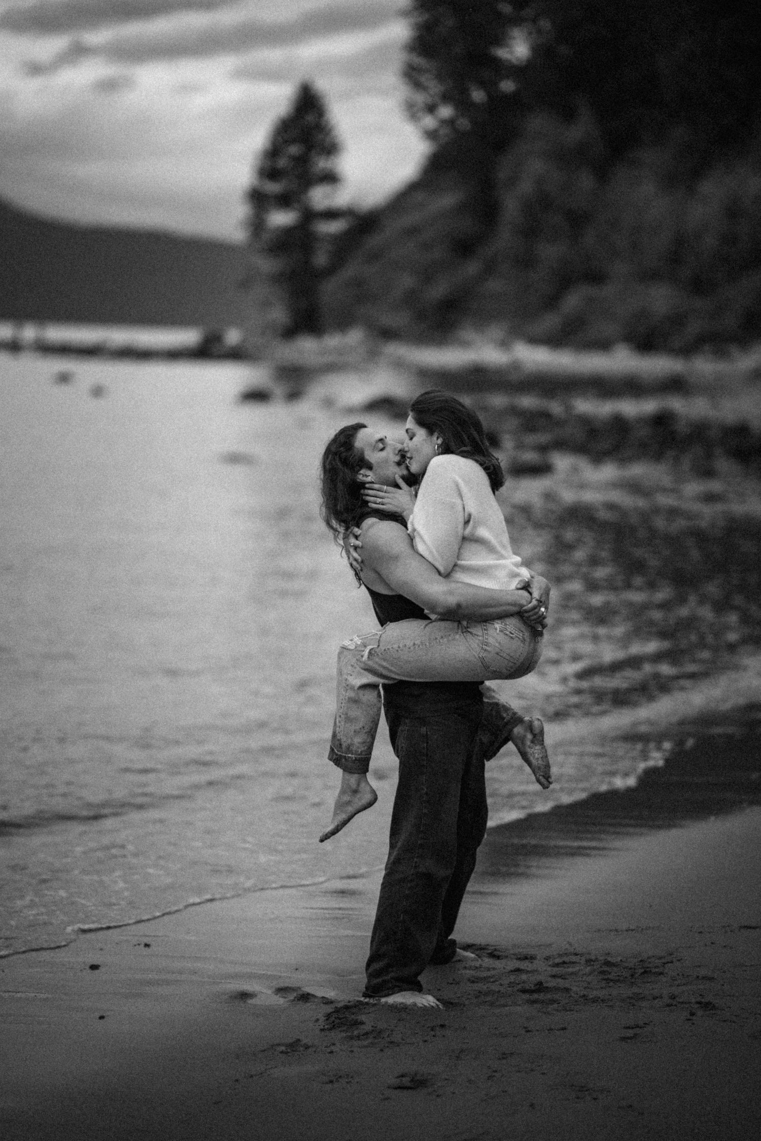 A romantic black and white photo of a couple dancing on a misty beach.