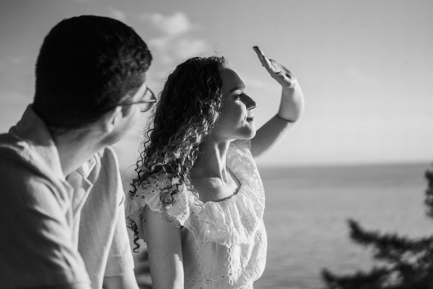 Black and white photo of romantic moments shared on an oceanside cliff.