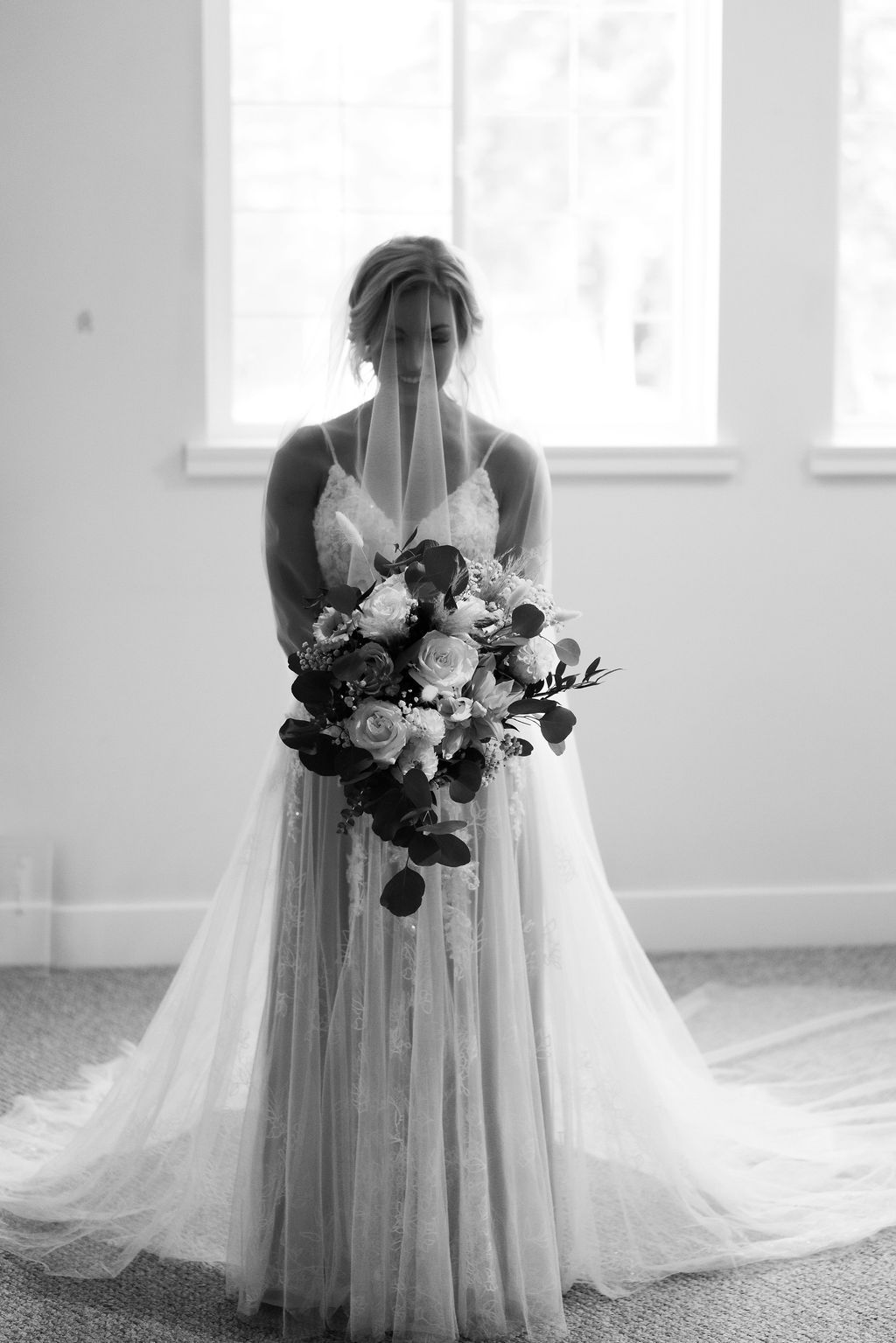 Beautiful bridal portraits in white featuring an elegant bouquet and flowing veil in natural light.