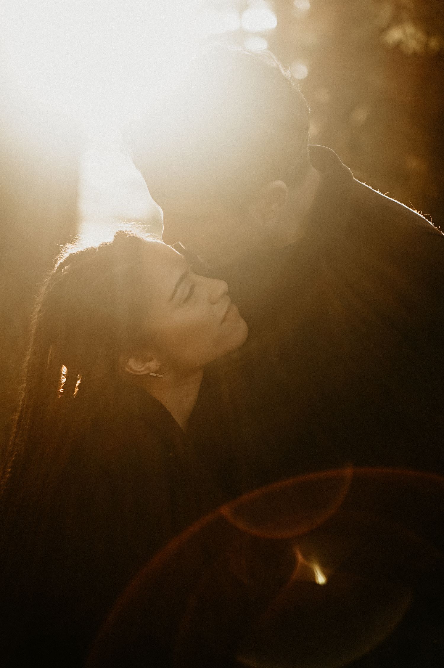 Silhouette figures stand close together in dramatic golden light creating an intimate atmosphere.