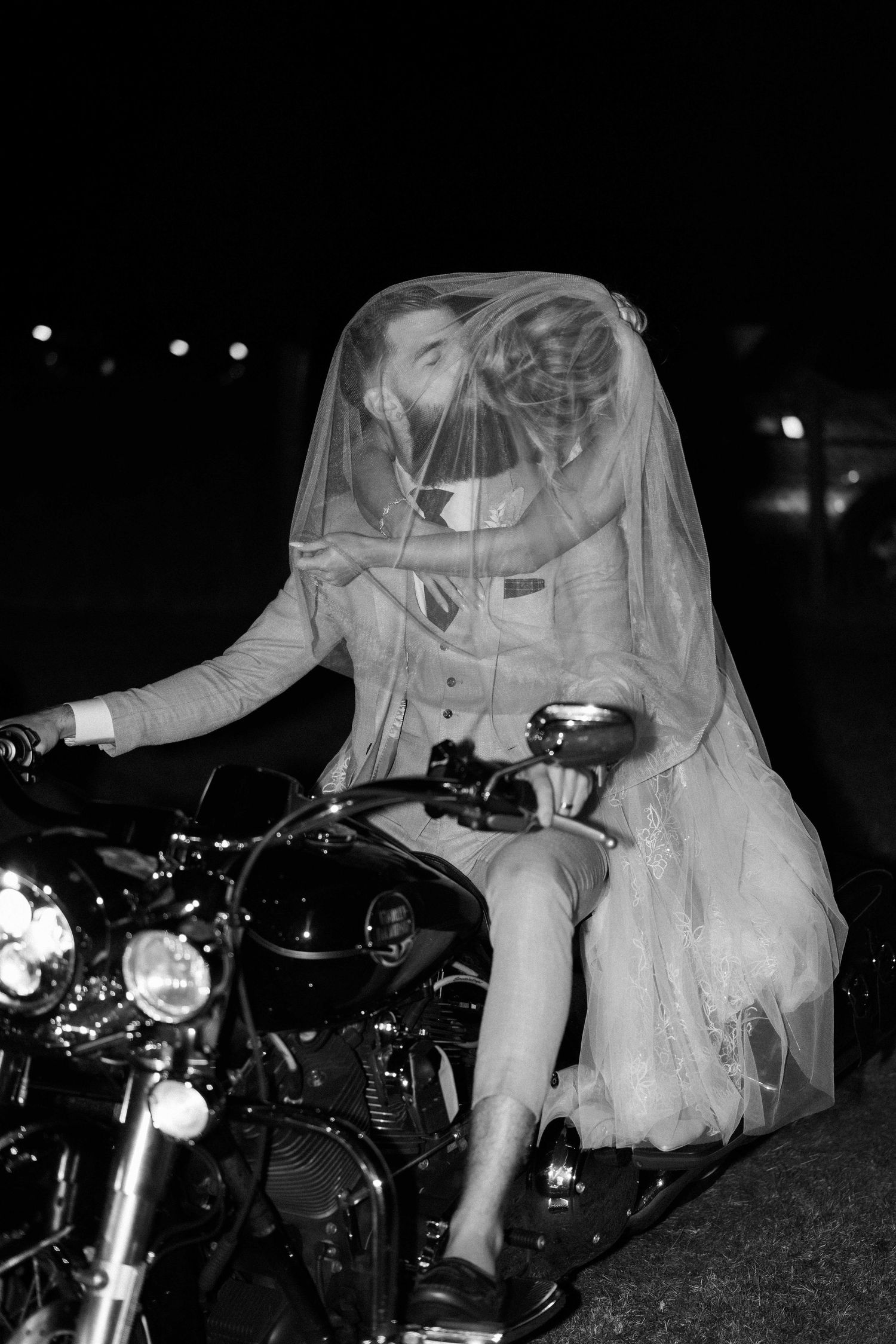Wedding couple posing with vintage motorcycles at night.