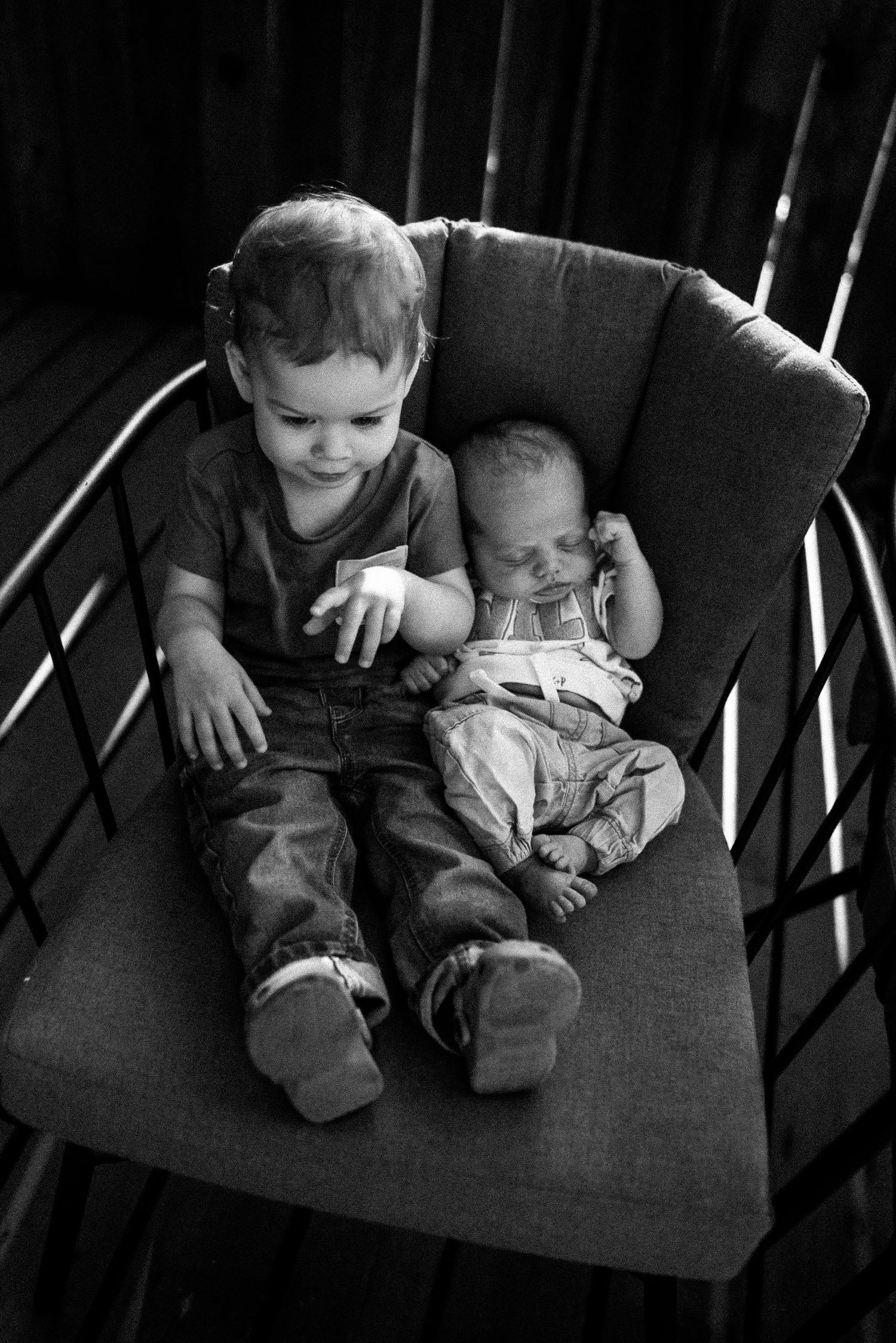 A series of black and white photos showing two children sitting together on a dark couch.