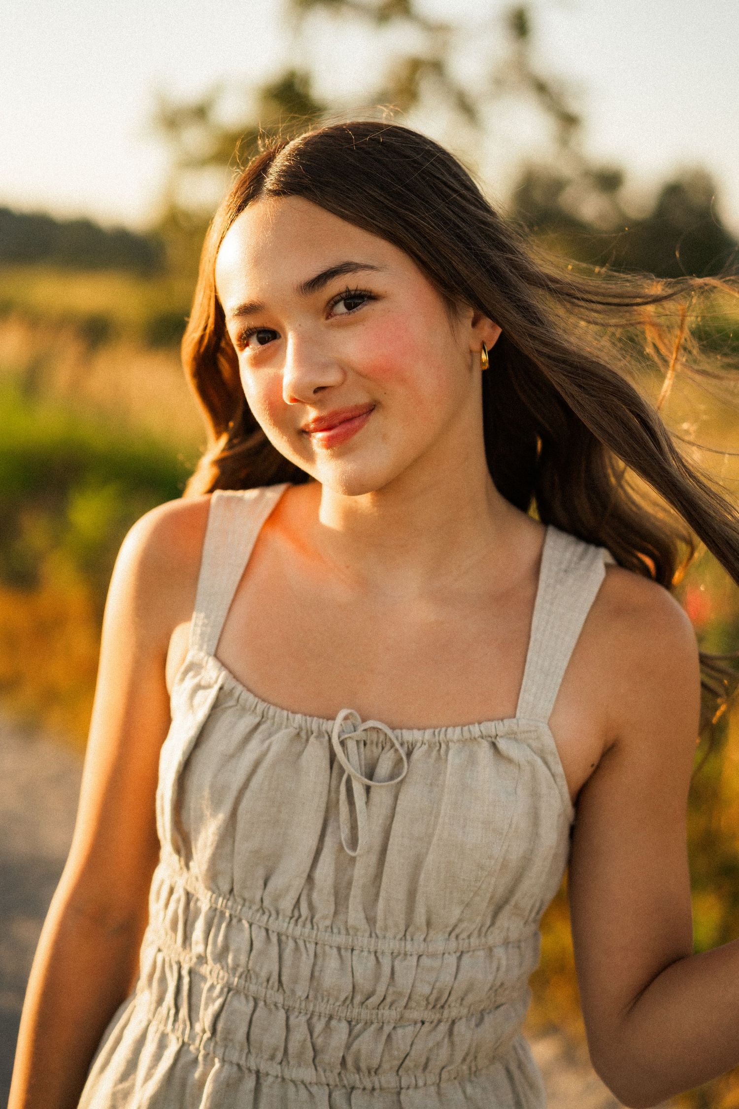 Portrait in sundress amid warm summer field at golden hour.