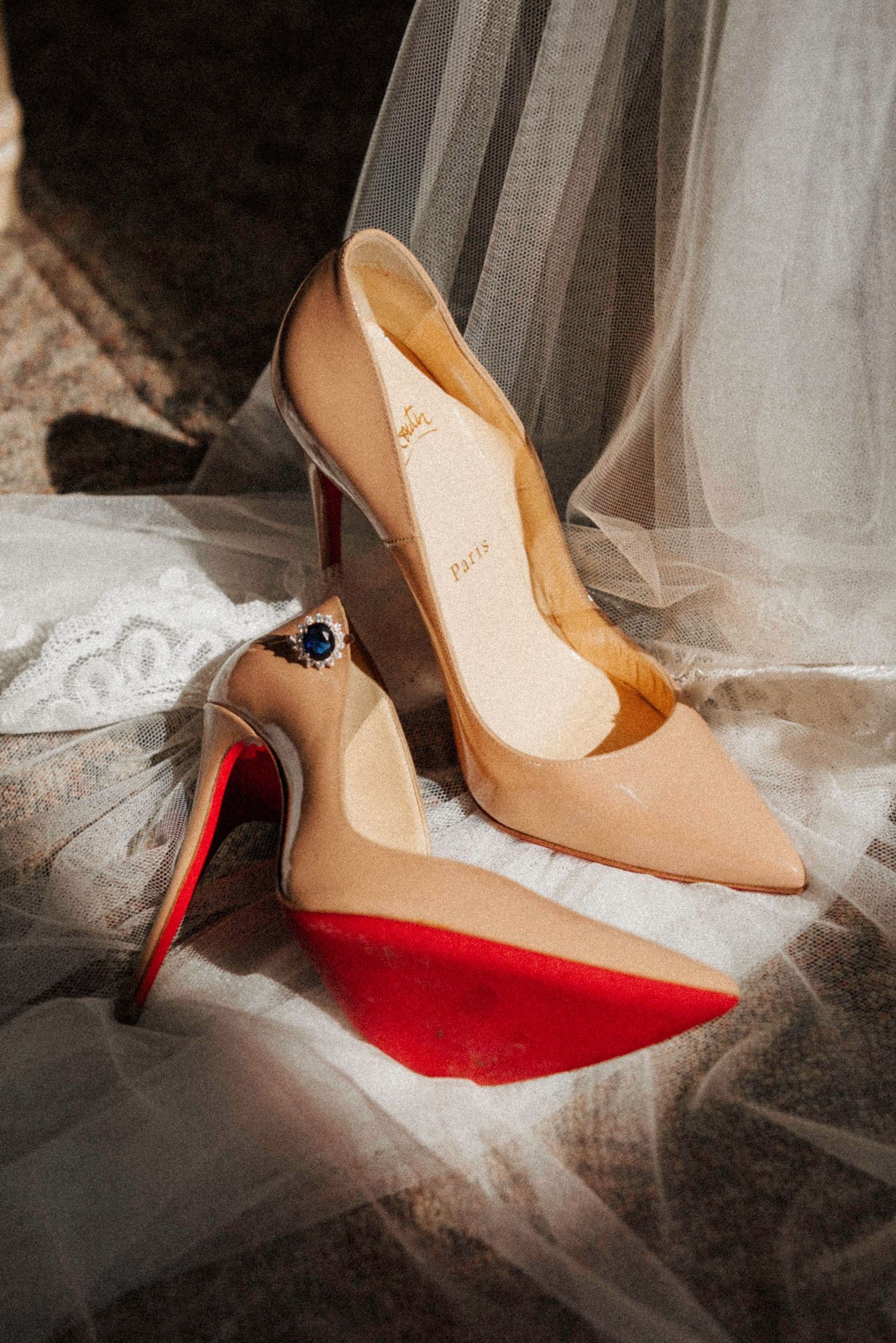 Close-up of elegant beige and red high heel shoes resting on white tulle fabric.