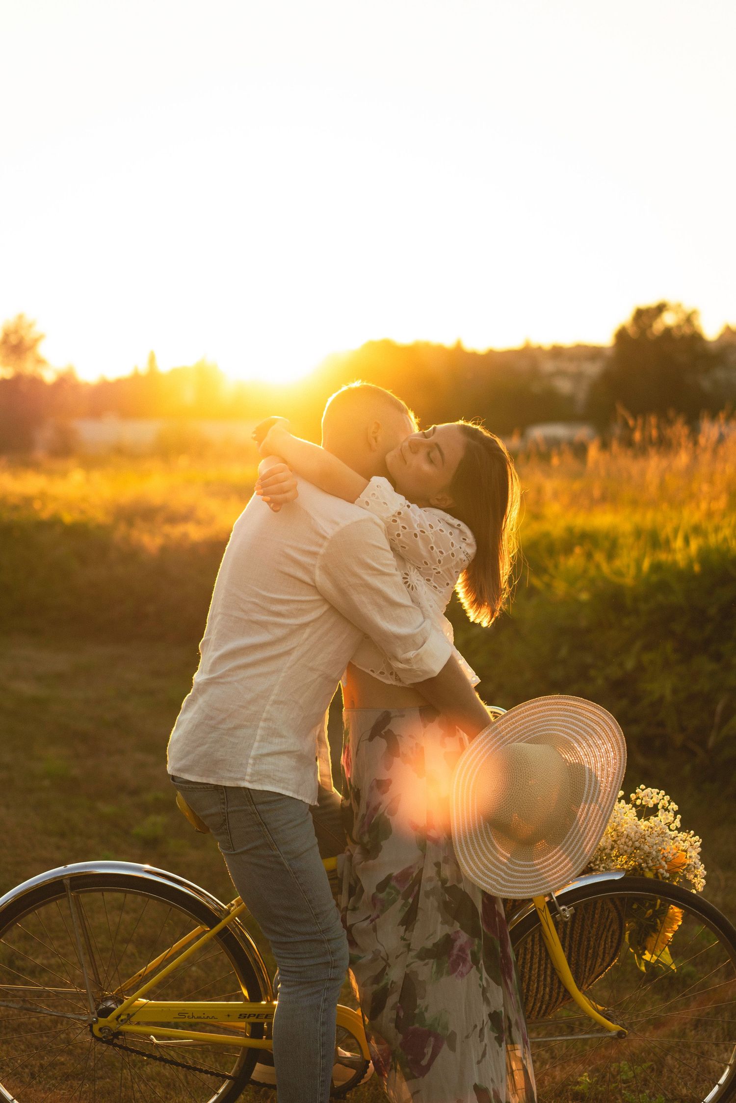 Couple sharing playful moment with bicycle during golden sunset.