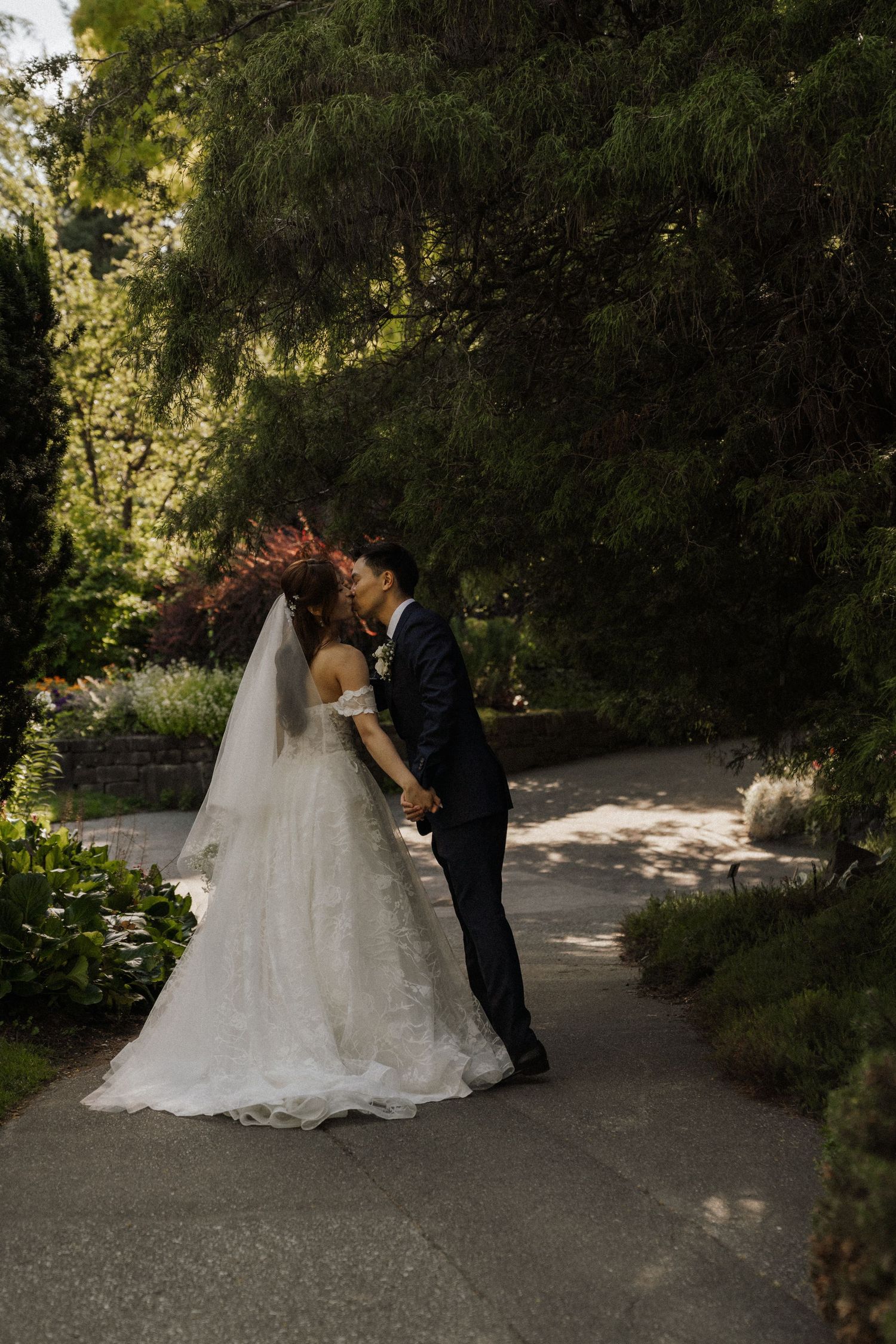 A couple shares a romantic moment in a garden setting during their wedding photoshoot.